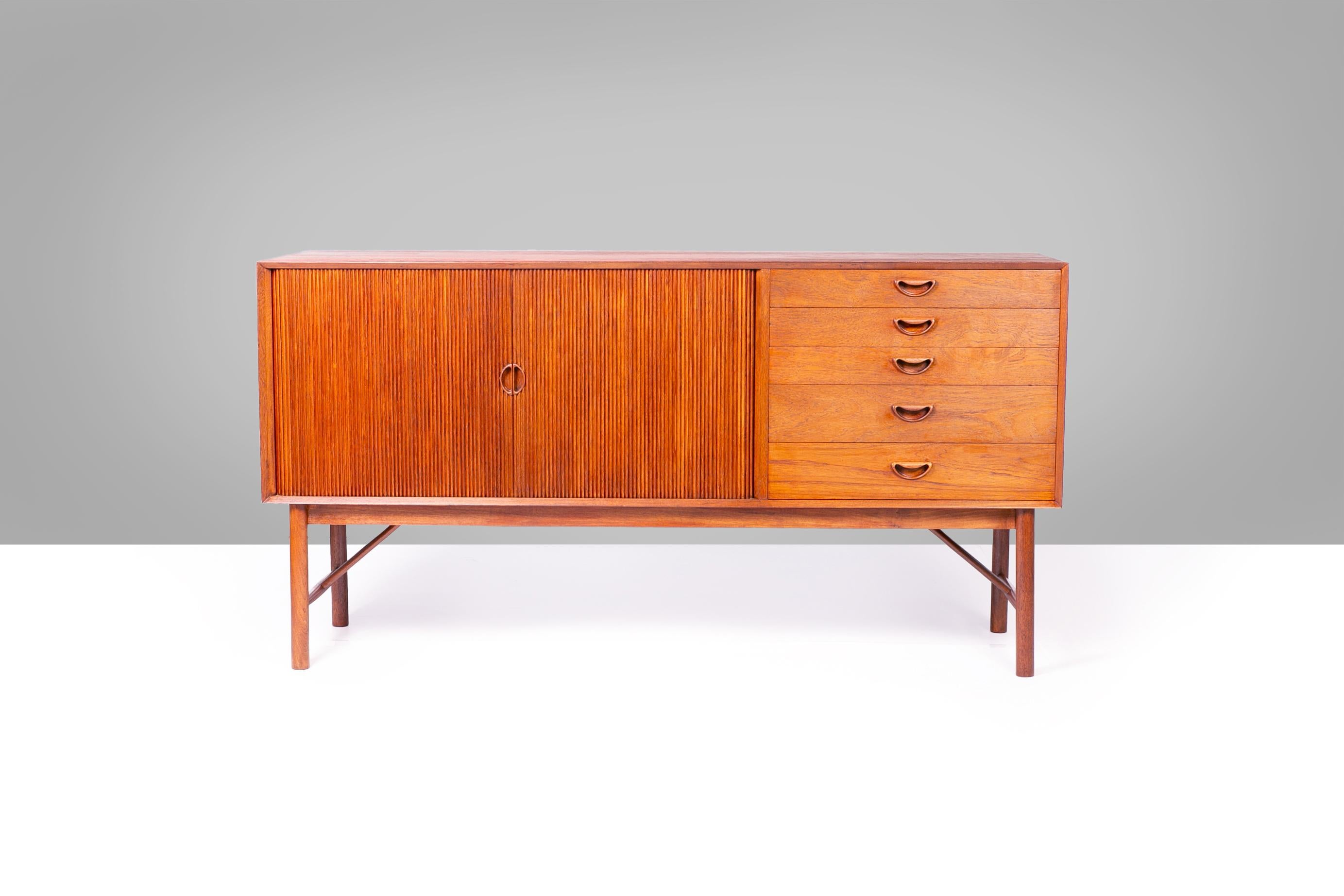 The Hvidt & Molgaard Tambour Door Sideboard (circa 1950s) by Søborg Møbelfabrik is a striking example of mid-century Danish modern design. Renowned for its minimalist elegance, the sideboard features sleek, curved tambour doors that elegantly roll