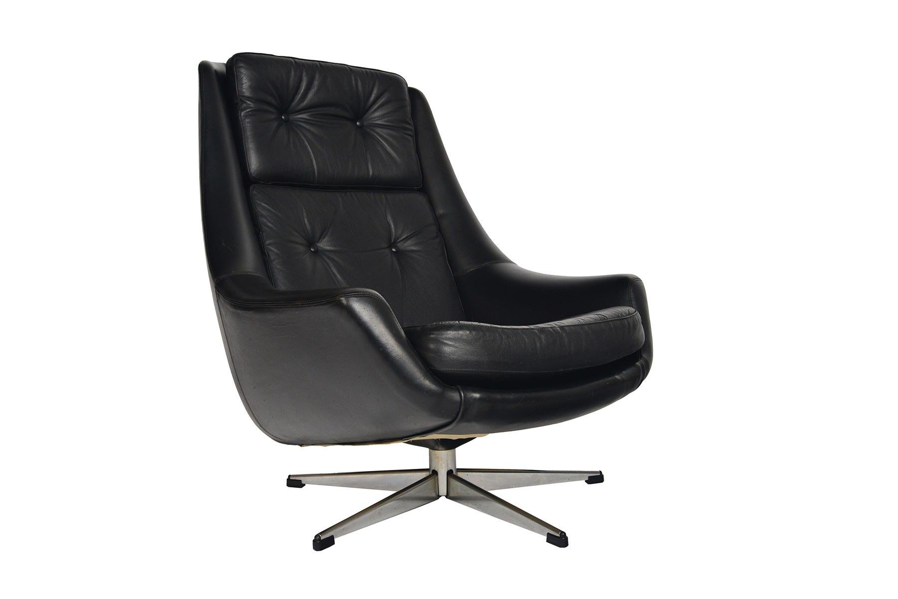 This wonderfully well- preserved swivel chair was designed by H.W. Klein for Bramin in the 1960s. With a sleek, organic form, this black leather lounge chair is upholstered on all sides and holds three button- tufted cushions. The swivel base offers