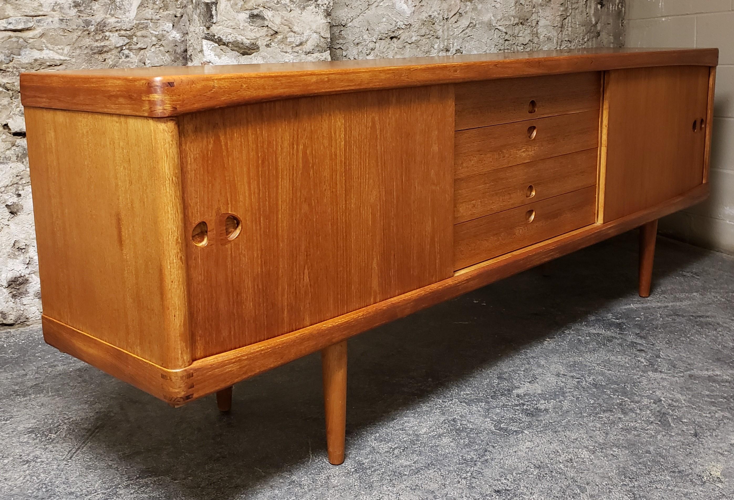 H.W. Klein teak sideboard / credenza for Bramin. It features beautifully contoured handles, corner inlay details and a finished back. It has 4 drawers with sliding doors on either side and round tapered legs. The interior shelving is adjustable.