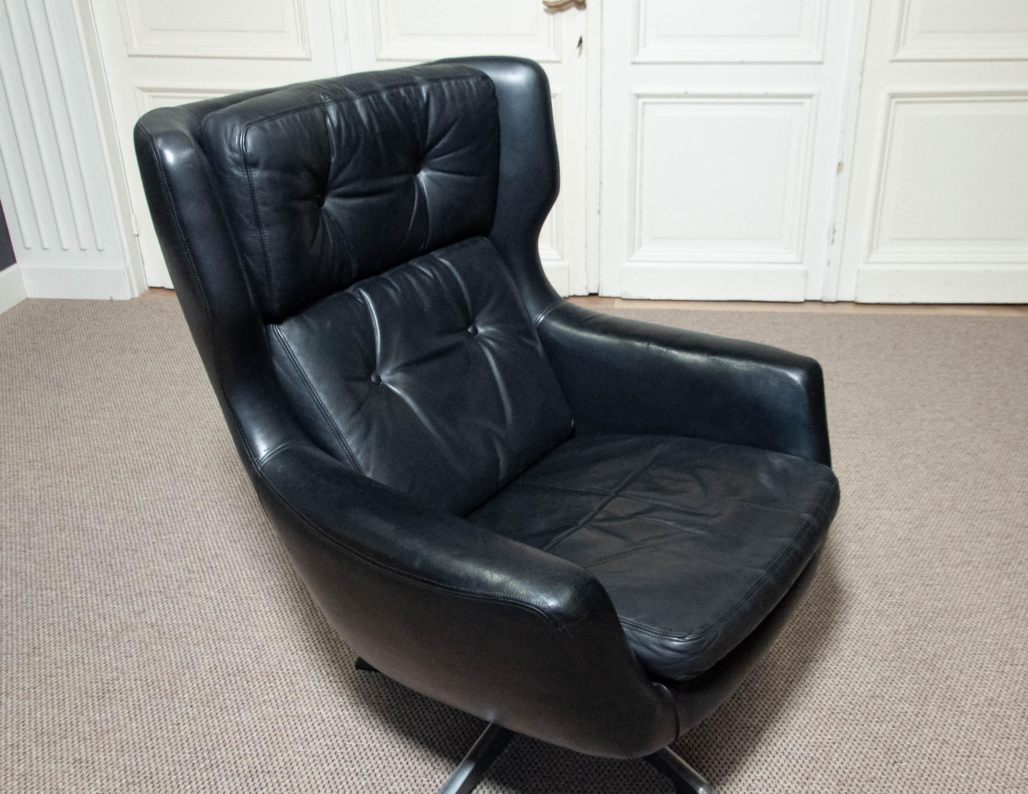 Ein atemberaubender Schaukelstuhl aus schwarzem Leder, entworfen von H.W. Klein für Bramin Møbler in den 1970er Jahren. Dieser kultige Ohrensessel mit getuftetem Lederbezug und einem eleganten Aluminium-Drehfuß bietet Komfort und Stil. Der Stuhl ist