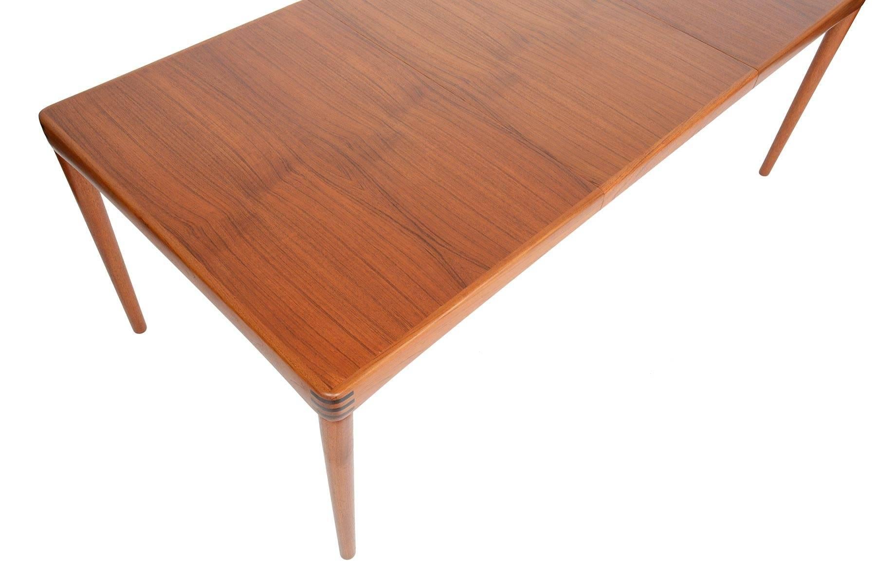 This stunning Danish modern midcentury dining table in teak was designed by H.W. Klein for Bramin in the 1960s. Beautiful banding is accented with Brazilian rosewood inlays around the corners. Table top expands to fit a single leaf and can