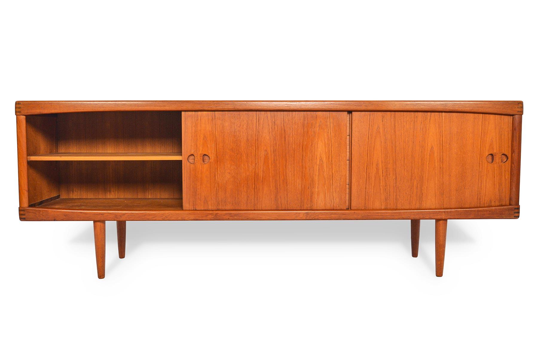 This breathtaking Danish modern midcentury teak credenza was designed by H.W. Klein and manufactured by Bramin in the 1960s. Left and right doors slide open to reveal adjustable shelving. Four center drawers provide additional storage. All doors and