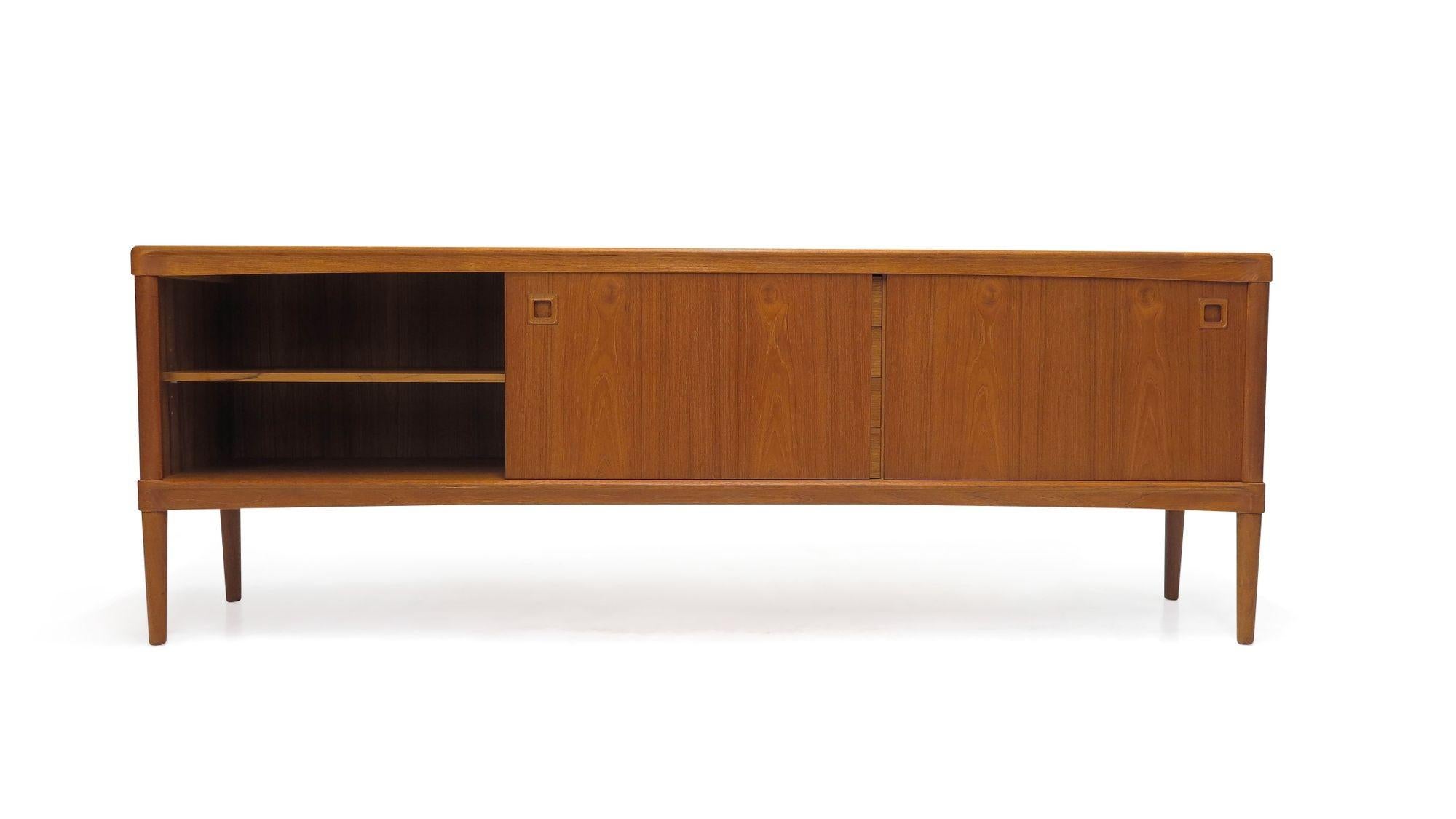 Danish Teak credenza designed by H.W Klein for Bramin Moblefabrik. Finely crafted of teak with book-matched grain and recessed square pulls. The cabinet has two sliding doors revealing an interior with adjustable shelves, and four drawers in center.