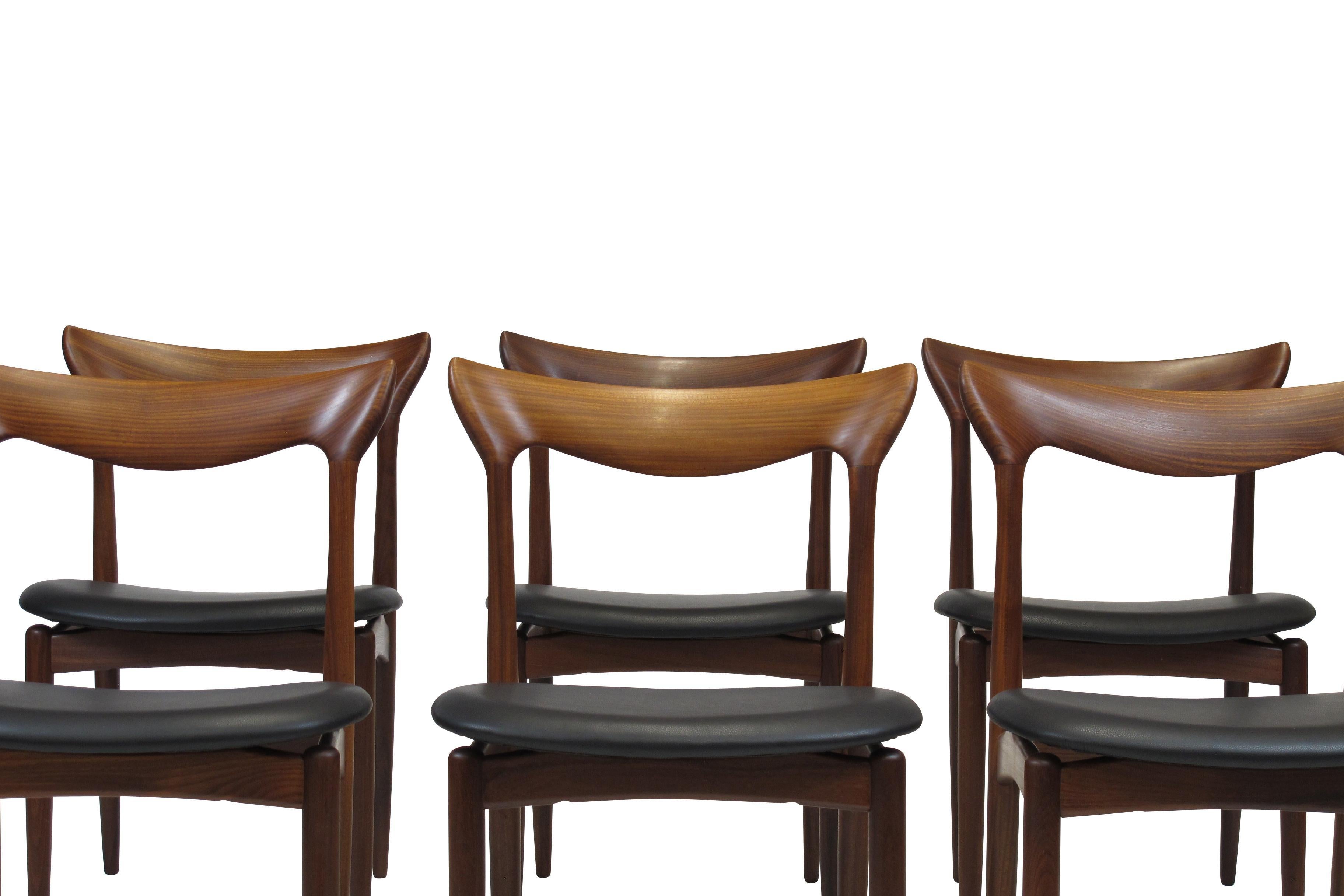 Exquisite set of six HW Klein teak dining chairs (circa 1960) with hand sculpted backrest, tapered leg, and floating seats newly upholstered in black leather. The chairs have been fully restored in a natural oil finish. Immaculate condition.
