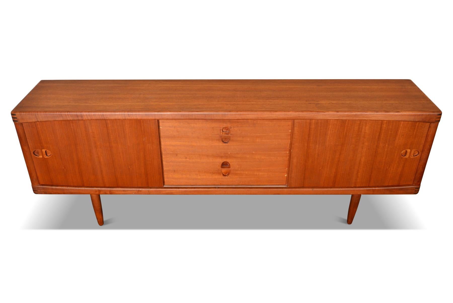 This breathtaking Danish modern midcentury teak credenza was designed by H.W. Klein and manufactured by Bramin in the 1960s. Left and right doors slide open to reveal adjustable shelving. Four center drawers provide additional storage. All doors and