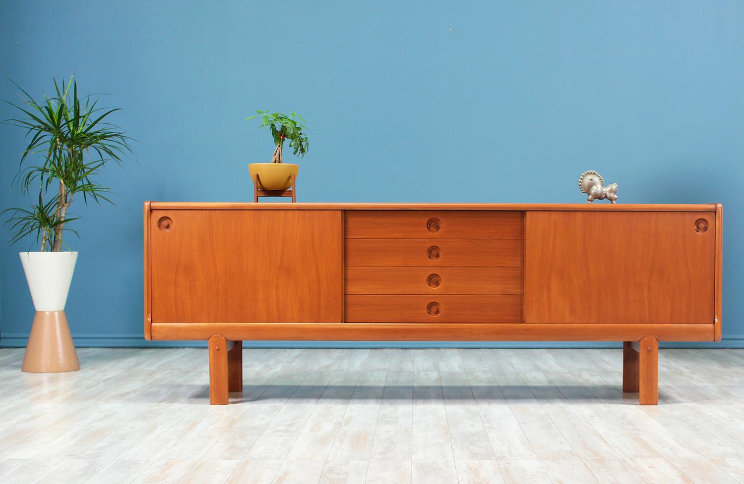 Beautiful credenza designed by H.W. Klein for Bramin Møbler in Denmark circa 1960’s. Impeccably crafted in teak wood, this spacious credenza offers four drawers in the middle and two sliding doors on each side with shelved compartments within. Each