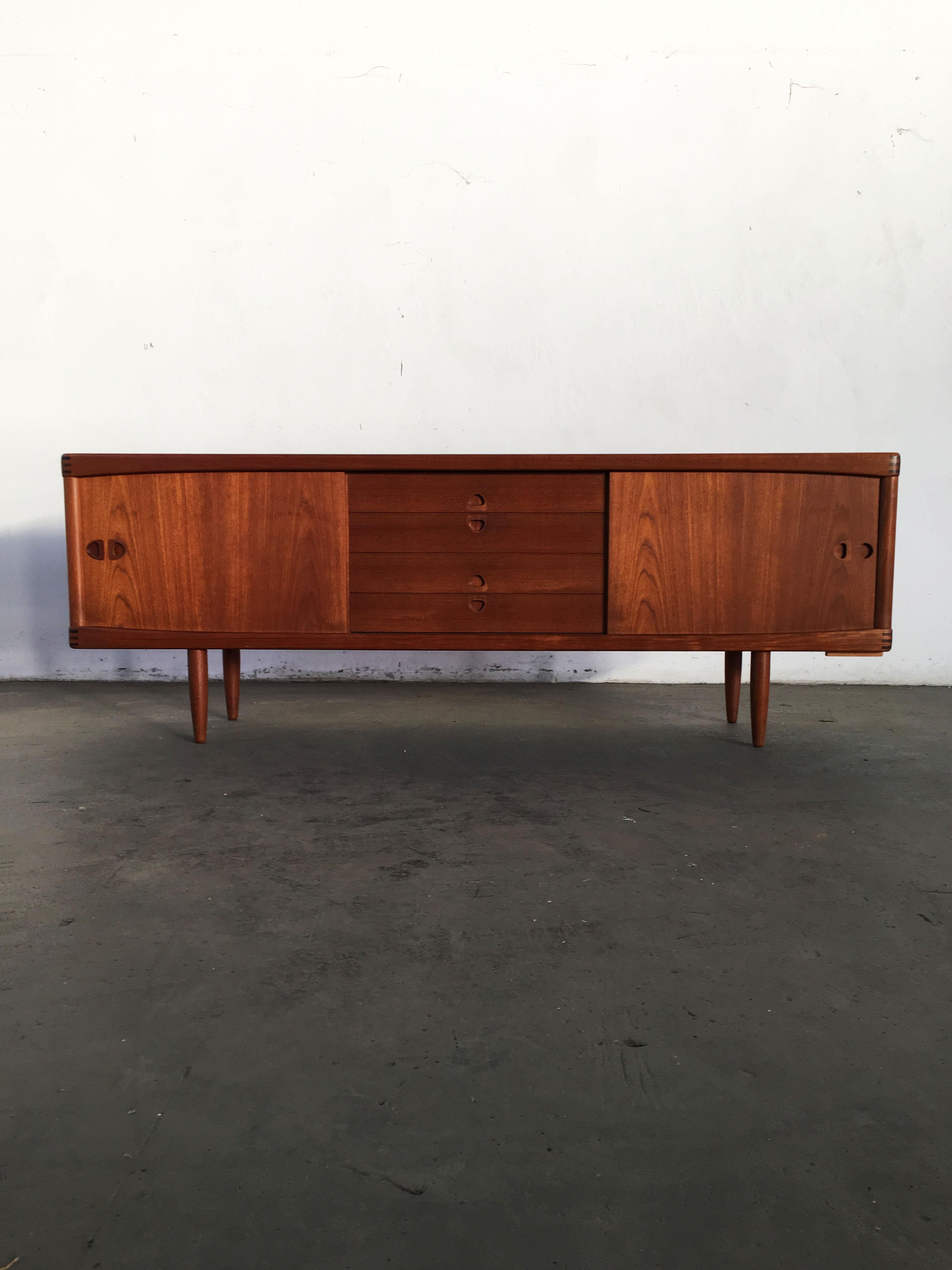 Superbly build solid teak sideboard by Danish designer Henry Walter Klein. Manufactured by Bramin Møbler, Denmark, 1960s. Beautiful teak grain on the front and top, comes with two sliding doors with adjustable shelves behind and four central