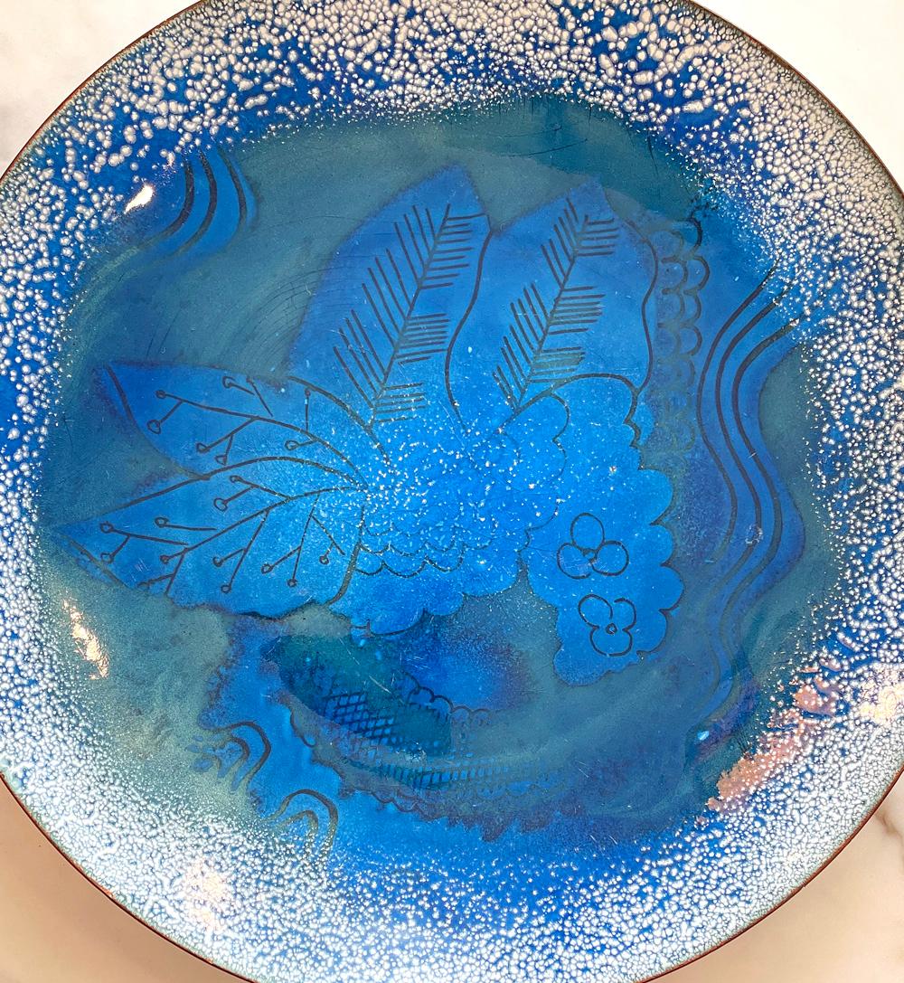 Created by Edward Winter, one of the masters of American enamel artistry in the 1930s, 40s and 50s, this low bowl features a composition of hydrangea flowers and leaves at its center, executed in deep, rich blues, with a rim dotted in a pattern of