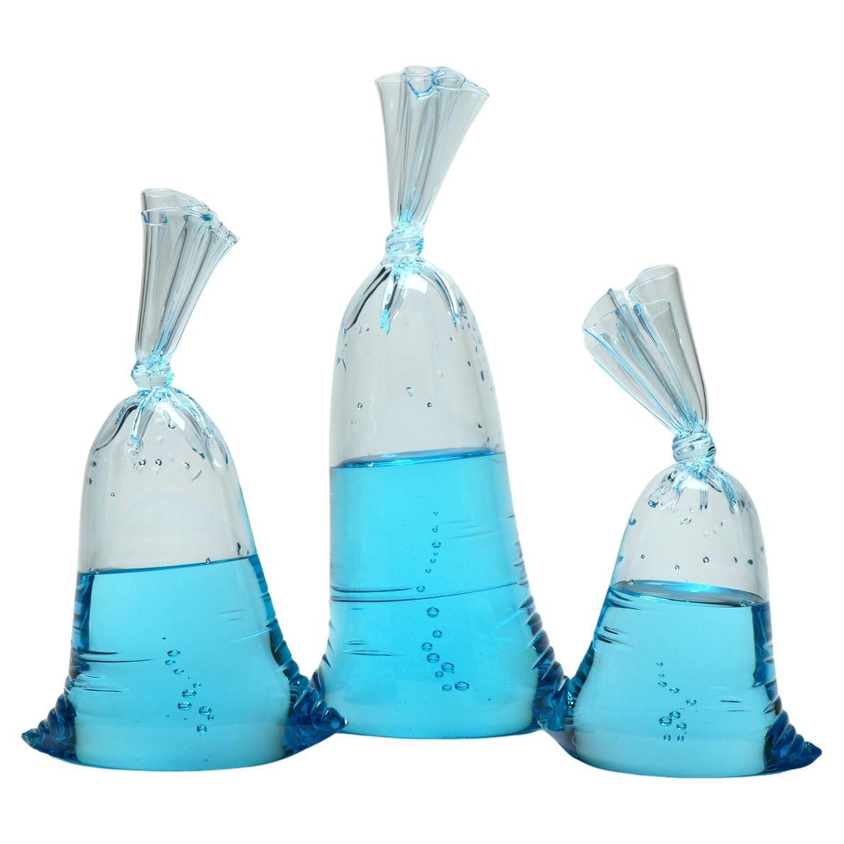 Hyperreal blue glass water bag trio sculpture installation