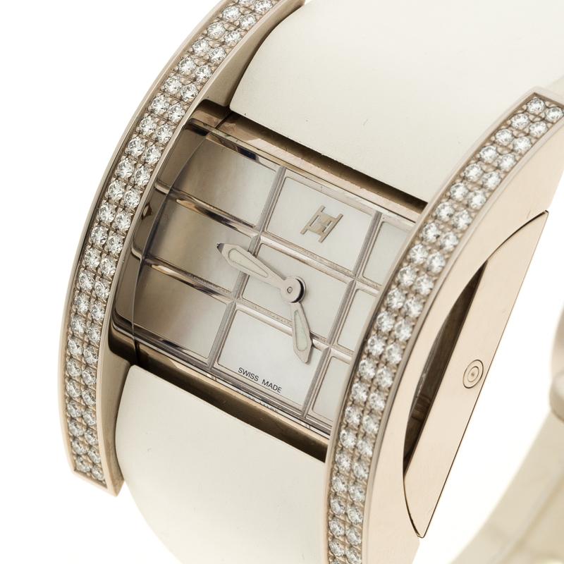 This Jorg Hysek’s wristwatch exudes luxury and minimalism. Set in a pristine white gold case the bezel is fixed lined with pave set diamonds. A Mother of Pearl dial adds to the grandeur with its silver-tone checked pattern. The logo at 12’ o clock