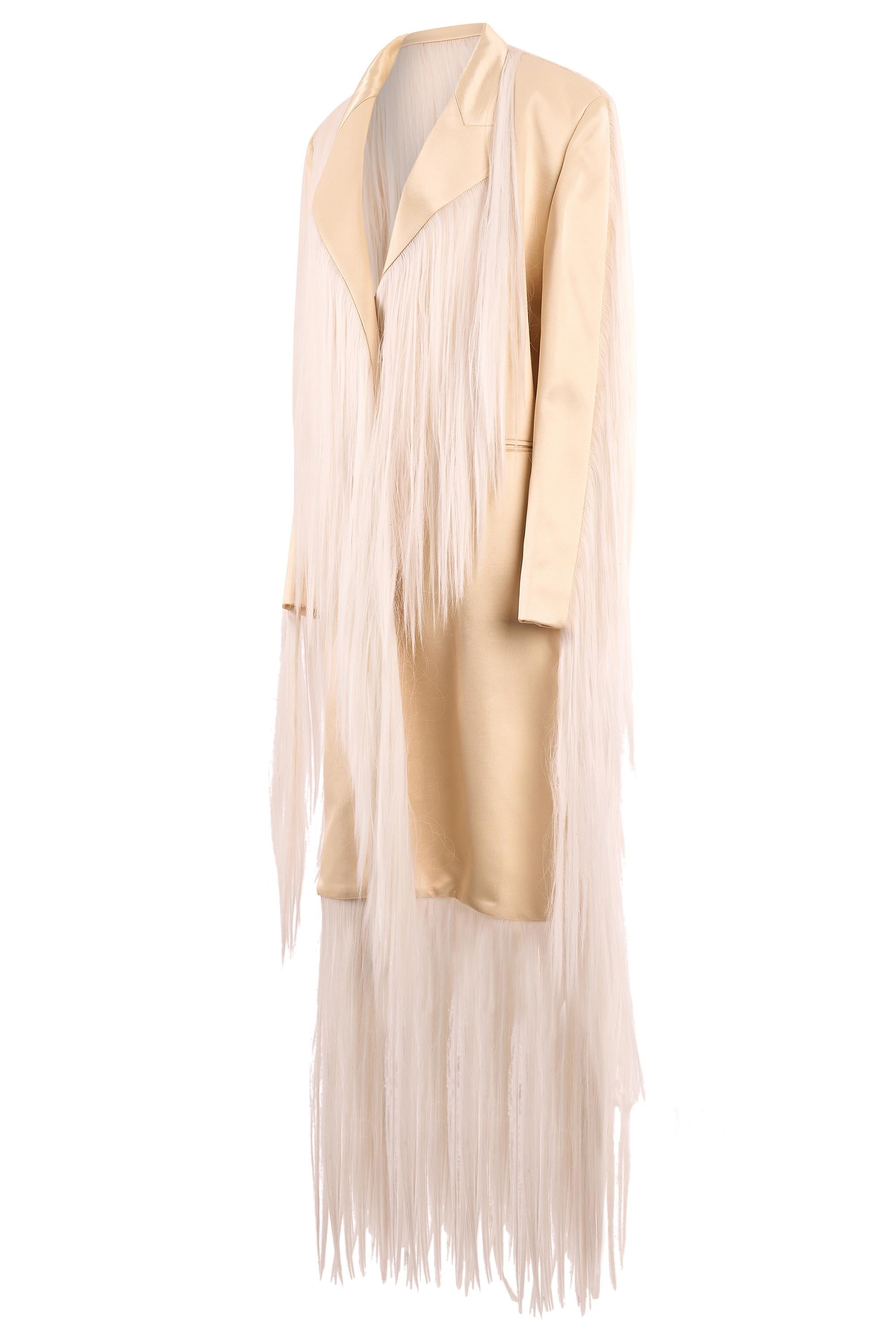 Hyun Mi Nielsen ivory fringe long hair coat from his Autumn Winter collection. This coat features dramatic fusion of tailoring and texture, .  base is crafted in a sleek ivory toned satin, cut into a sharp, elongated blazer-inspired shape. Cascading