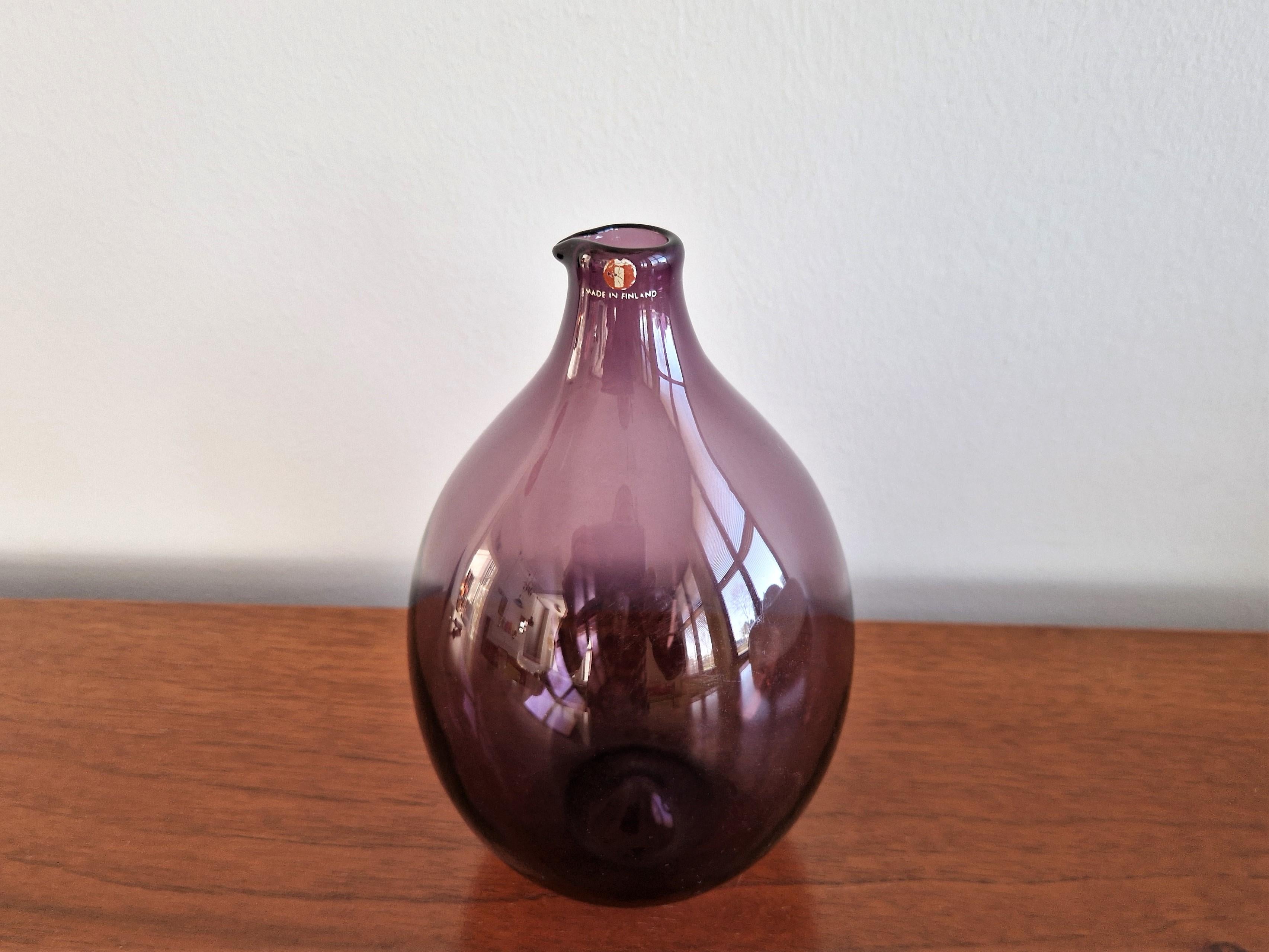 This purple glass 'Bird' bottle or vase was designed by Timo Sarpaneva for Iittala in Finland in 1956. It was in production from 1957 to 1966 and was available in various colors. It is in a very good condition with minor signs of age and use. It is