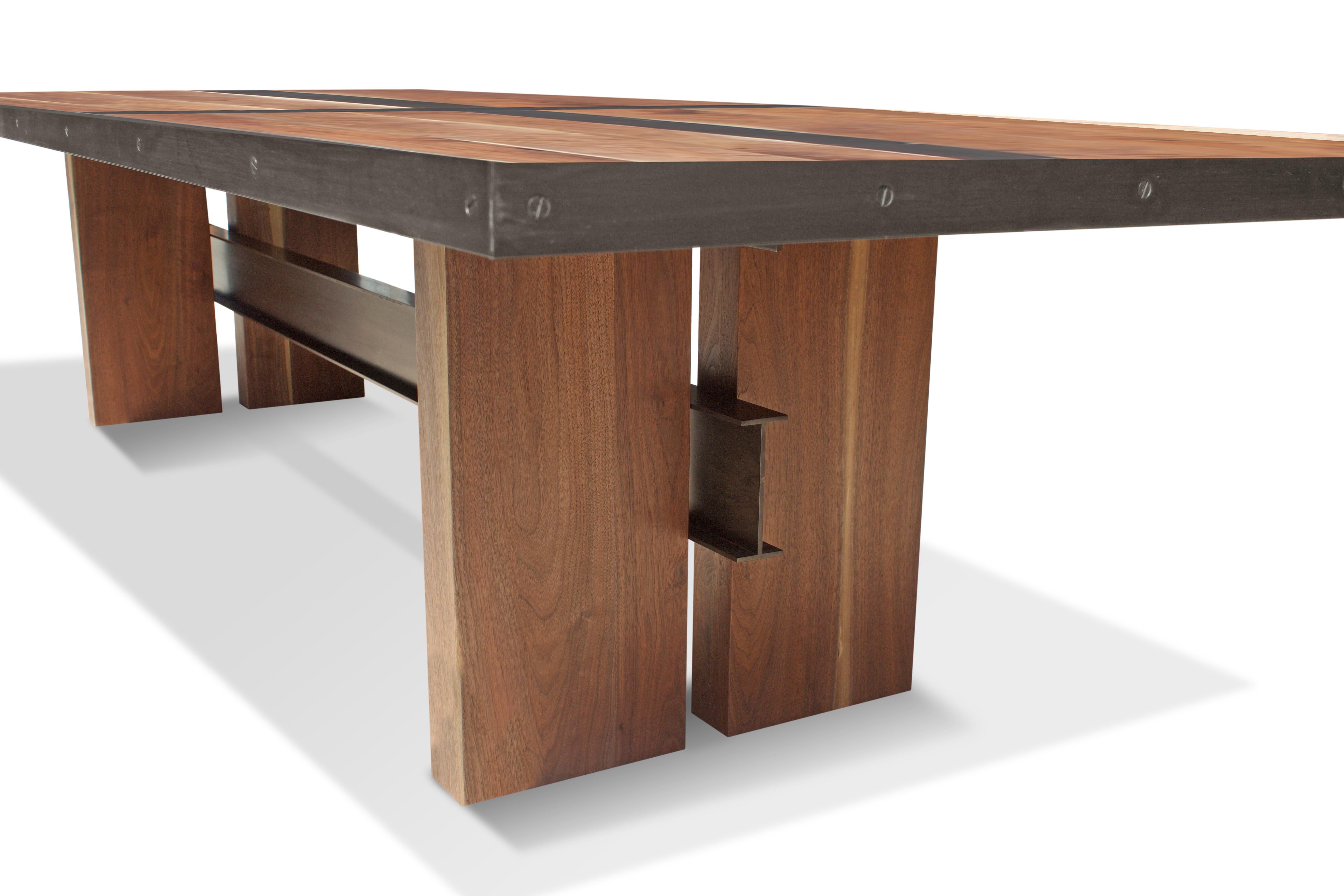 Made from reclaimed white oak with an antique stain, this conference table is a mix of strength, elegance and vision. The main feature of the structure is a fabricated I-Beam trestle. The dark steel sections complement its symmetrical, striking