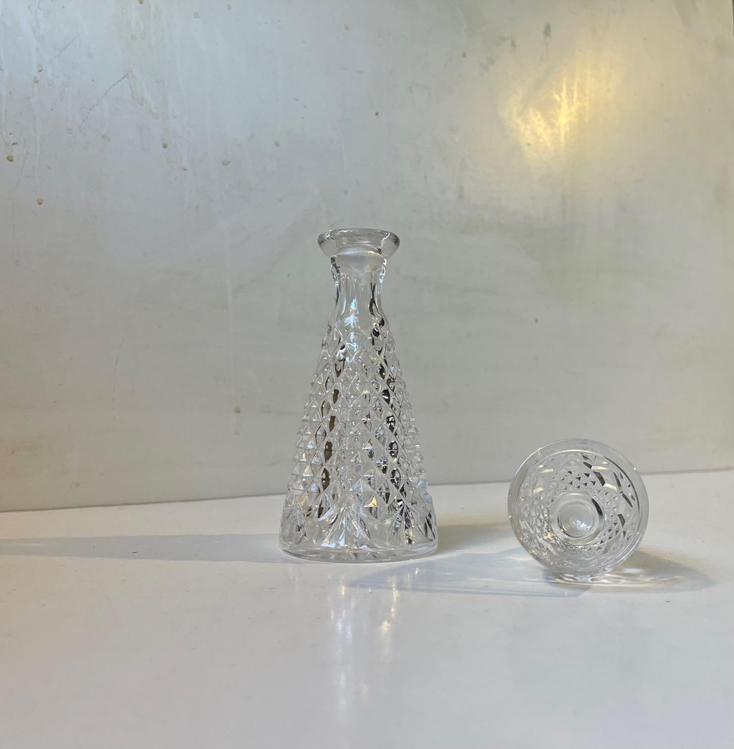 Small diablo-shaped crystal decanter cut with diamond patterns and set a stopper that is also a 6 cl glass. In the Czech Republic these are commonly called 'I drink solo'. It has a capacity of roughly 0.25 liter. Measurements: H: 19,5 cm, Diameter: