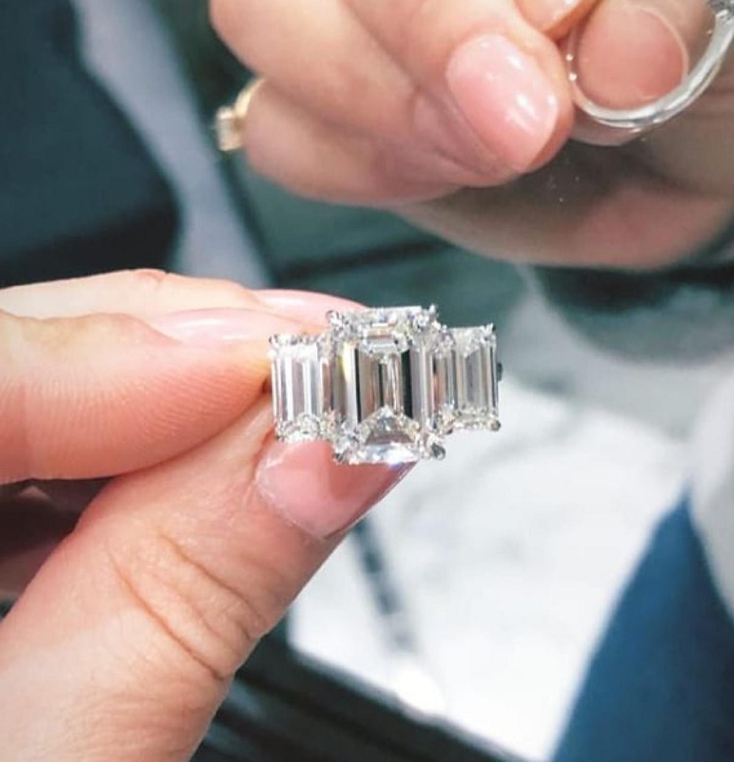 This gorgeous three stone ring has a main stone an emerald cut diamond that weights 3 carat has vvs2clarity and I color but a very white face, excellent polish, excellent symmetry and none fluorescence.

