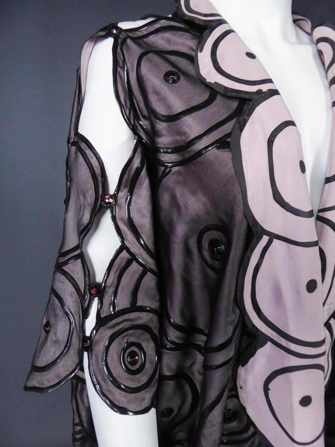Circa 1985/1990
England

Kaftan or evening kimono in rubber-painted silk by Ian & Marcel, creator of a London avant-garde brand from the end of the 1980s. Kaftan cut with wide slashed sleeves on the arms and shoulders. Totally innovative material in