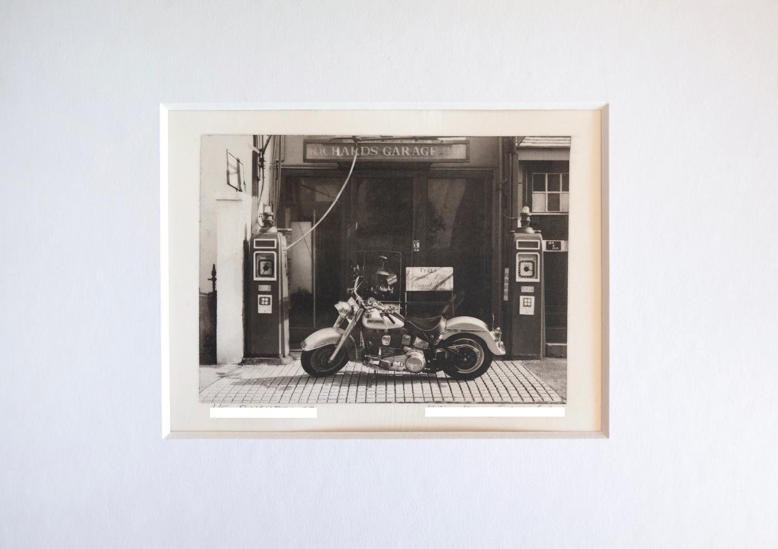 Brighton 27 -    Platinum Palladium print over silver on vellum paper - Edition 1 of 8 , plus 2 AP ( size 1 )
An old Harley Davidson motorcycle in front of a gas station garage in Brighton, UK, in 1984.

Signed + numbered with certificate of