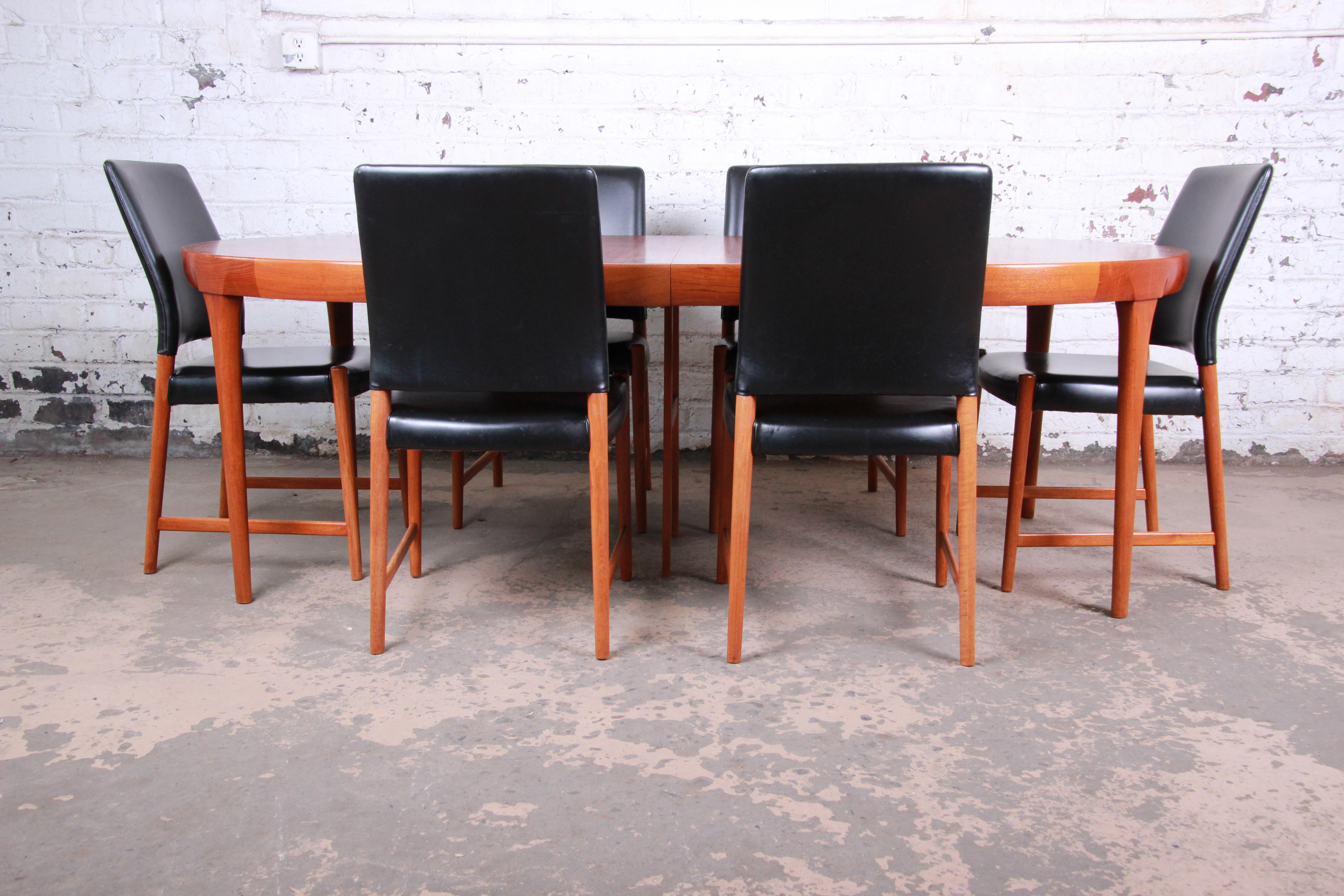 An exceptional Scandinavian Modern dining set. The teak extension dining table is designed by Ib Kofod-Larsen for Faarup Møbelfabrik. The table features gorgeous teak wood grain with solid sculpted teak legs and sleek Scandinavian design. Made in