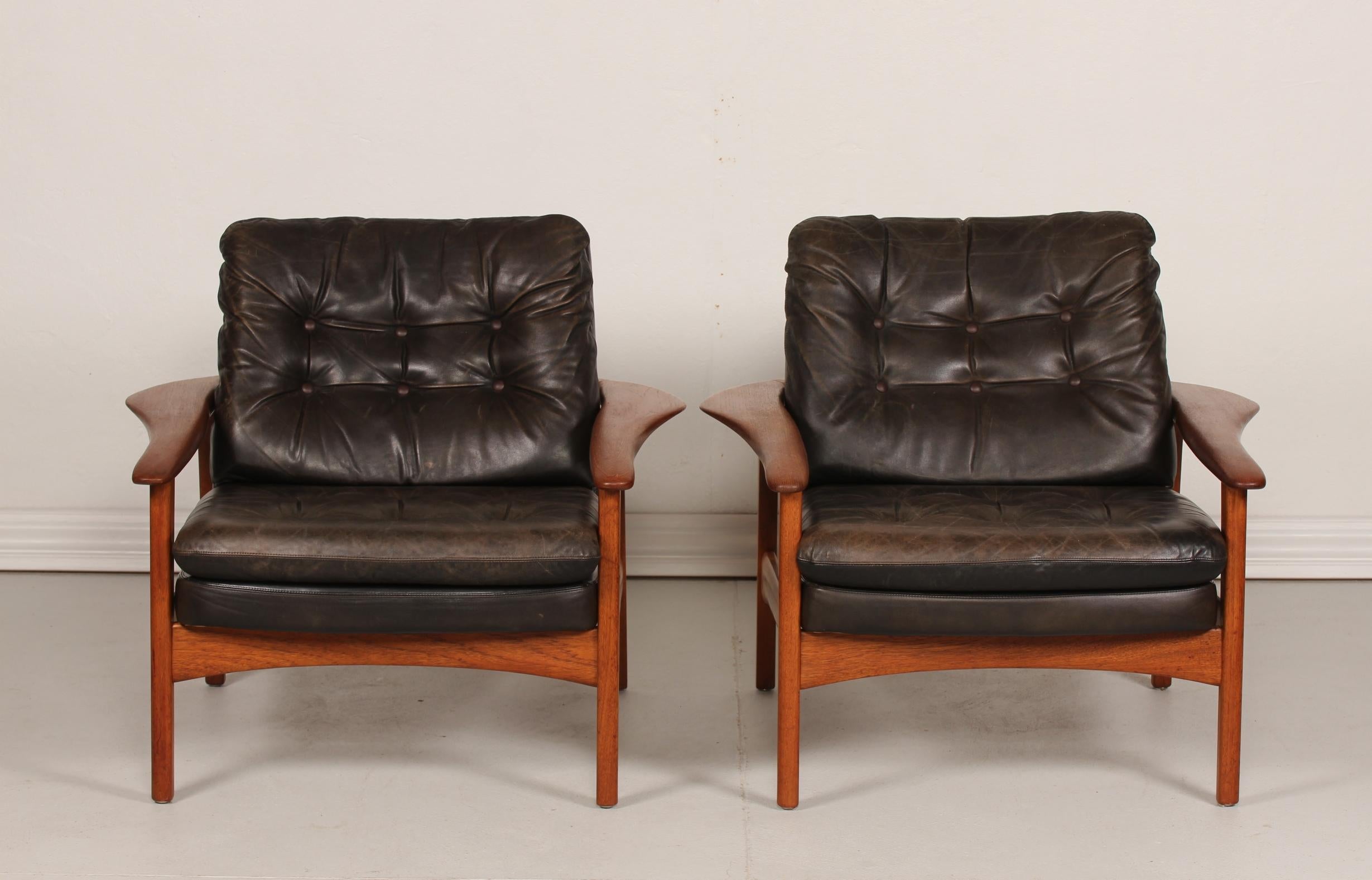 Pair of large vintage lounge chairs attributed to the Danish architect Ib Kofod-Larsen (1921-2003)
They are made of solid teak and have black leather cushions with good patina. The wood has been treated with teak oil.
 