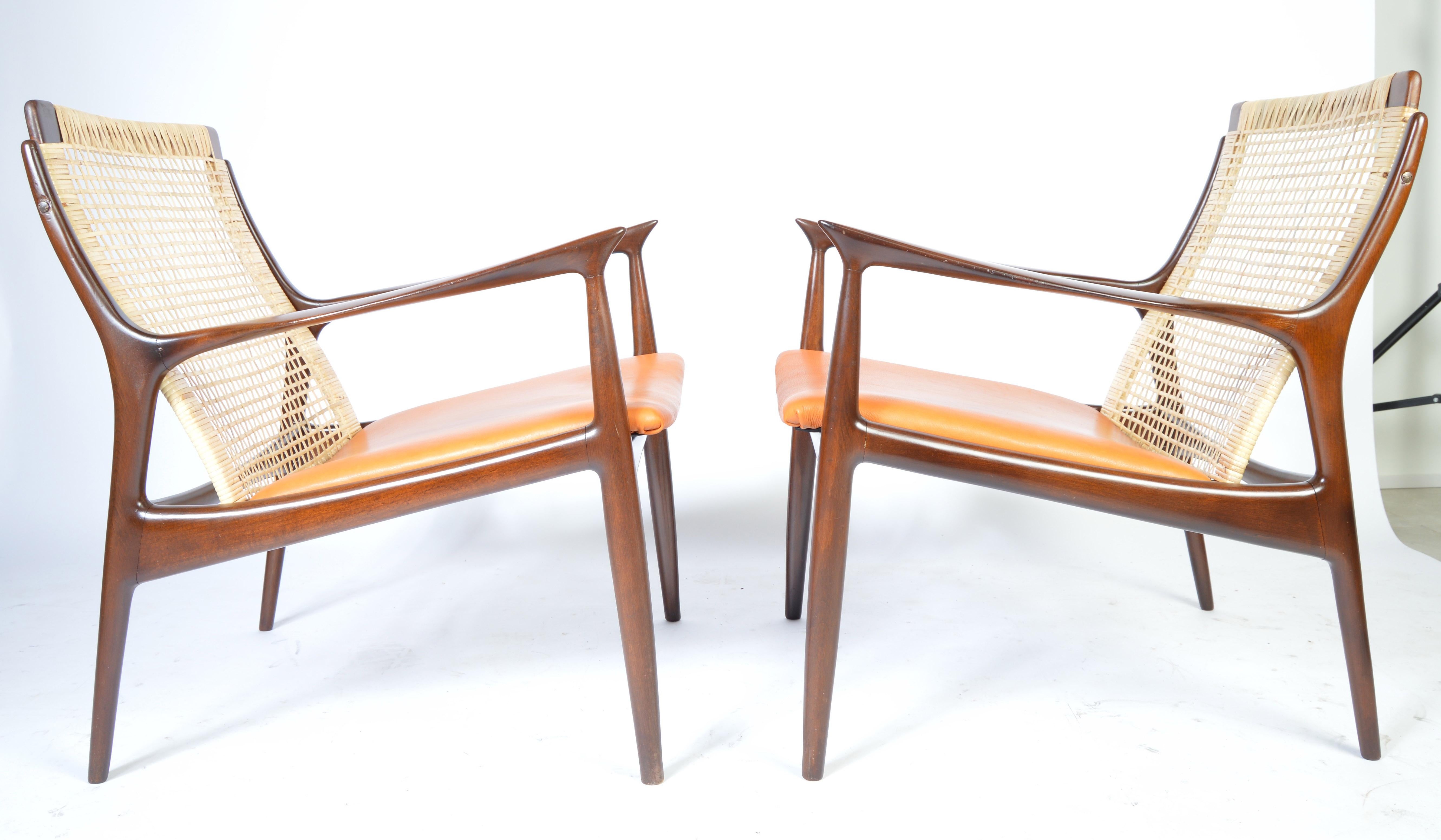 A stunning pair of IB Kofod Larsen easy chairs having cane backs, mahogany frames and supple vegetable dyed burnt orange seats.
Mint condition cane backrests.
Newly treated and well maintained mahogany frames.
Mild signs of use to leather.