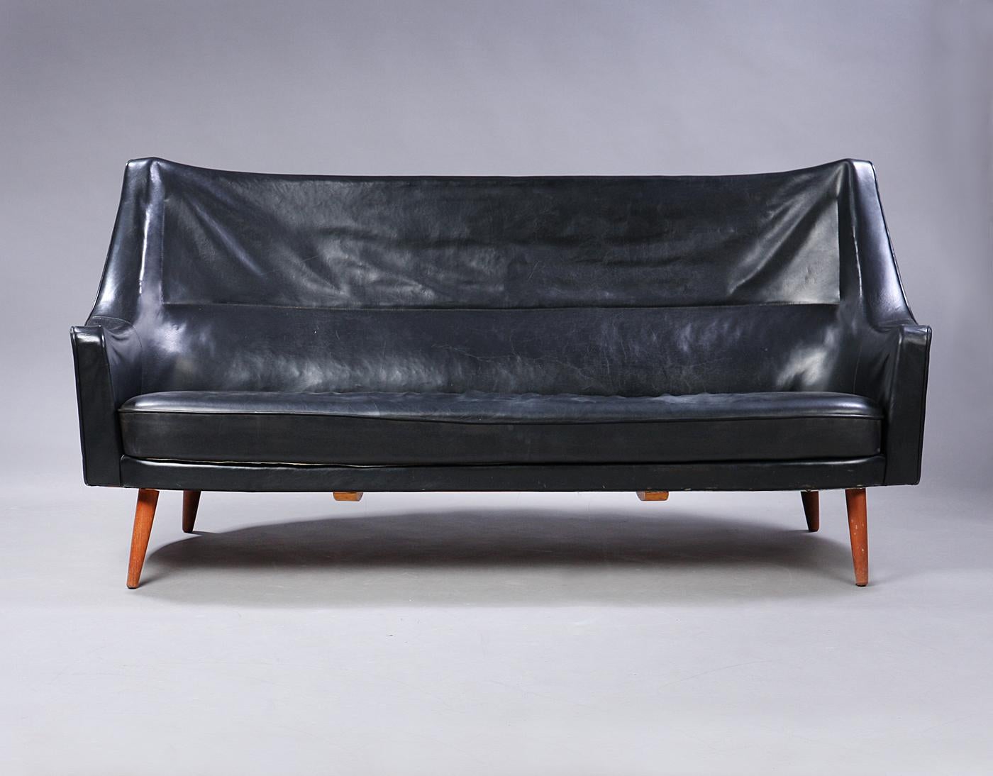 Very rare Ib Kofod Larsen 1921-2003. Sofa with curved back, back and sides upholstered in black original patinated leather, seat cushion with later black leather cover, teak frame. Presumably manufactured by Harald Gjernøe, or Christensen & Larsen.