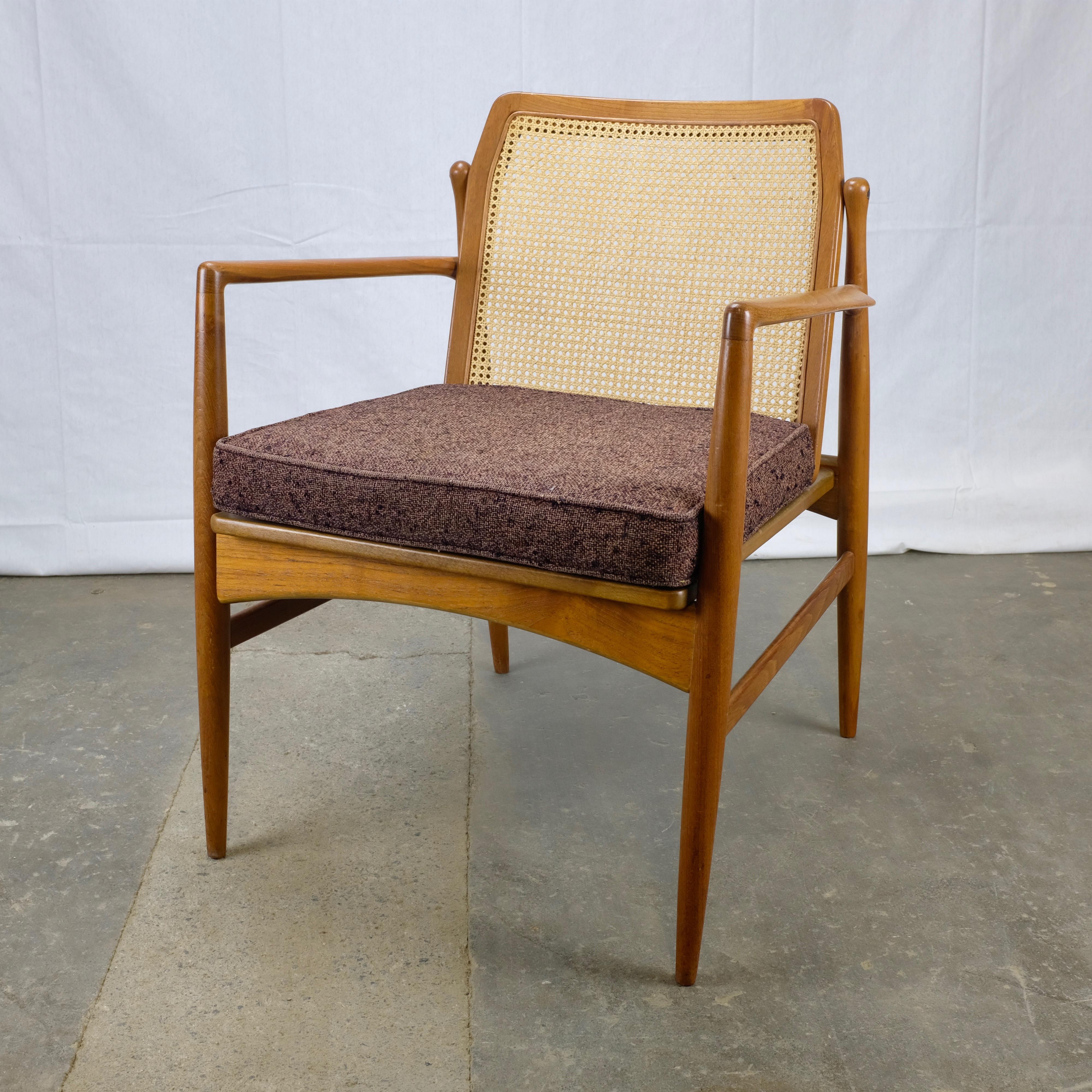 Teak armchair designed by Ib Kofod-Larsen and made in Denmark by Selig. It features a distinctive cane back, and the rear legs terminate in unique 'bulbs' that join the back frame to the legs. The chair has elegant upward-sloping armrests that are