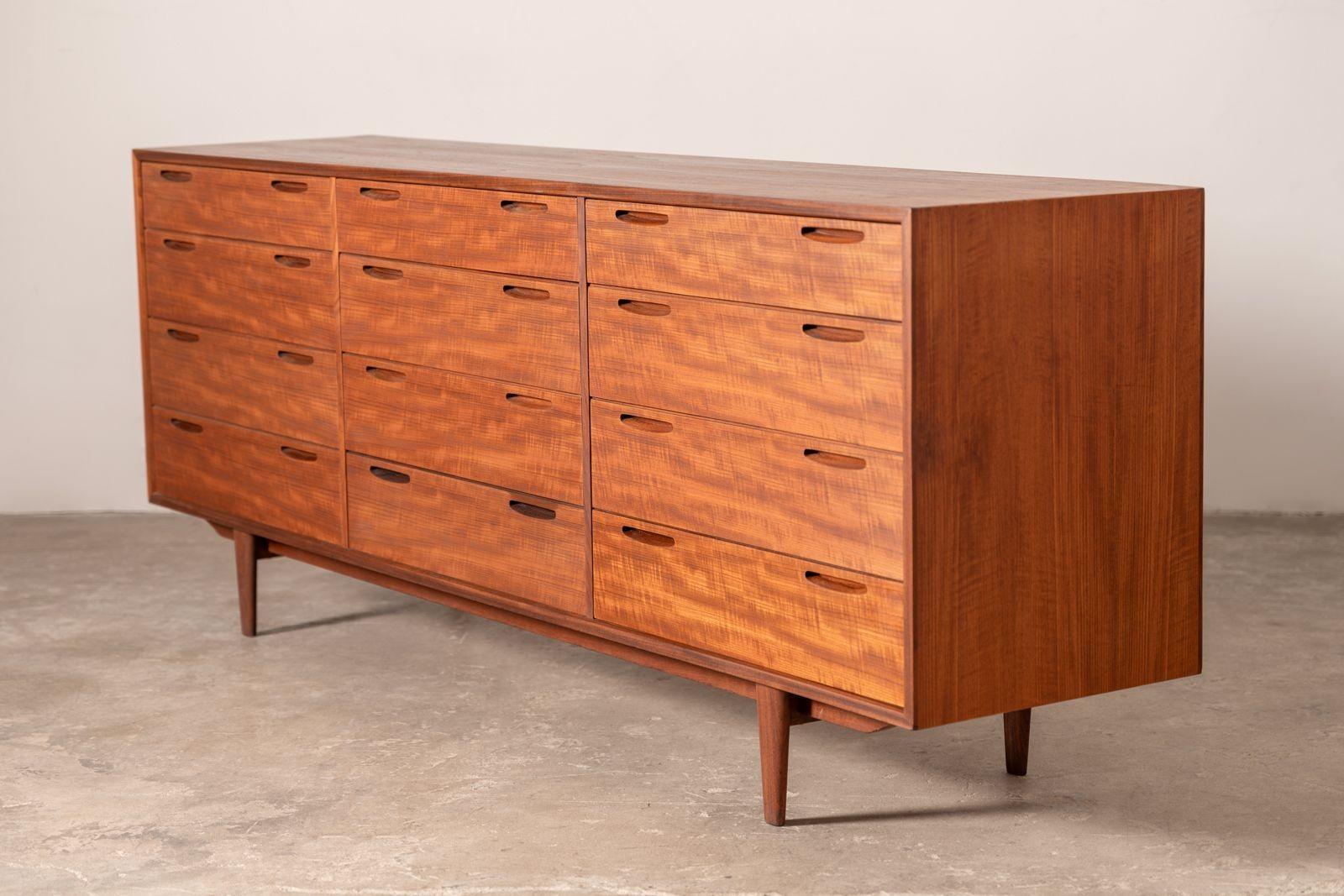 Ultra sleek twelve-drawer teak cabinet with a finished back. It can be utilized as a freestanding sideboard or would serve nicely as a dresser. Designed by Ib Kofod-Larsen and crafted of teak in Denmark by Brande Mobelfabrik.