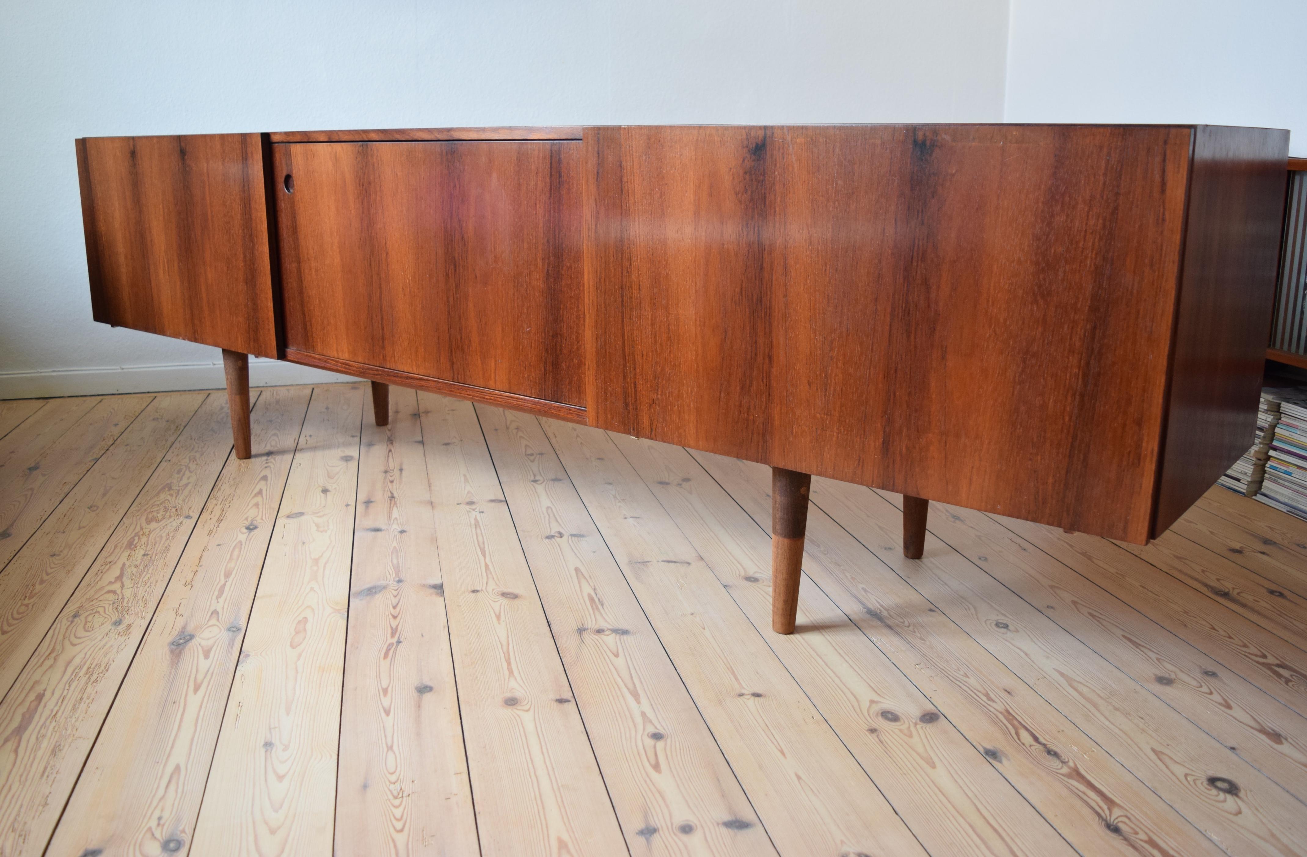 Very long and low credenza by Ib Kofod Larsen manufactured in Denmark in the late 1960s-early 1970s. Rosewood with maple interior and oak drawers. Sits on turned and tapered two-tone teak legs. Very deep with plenty of storage space. Three small