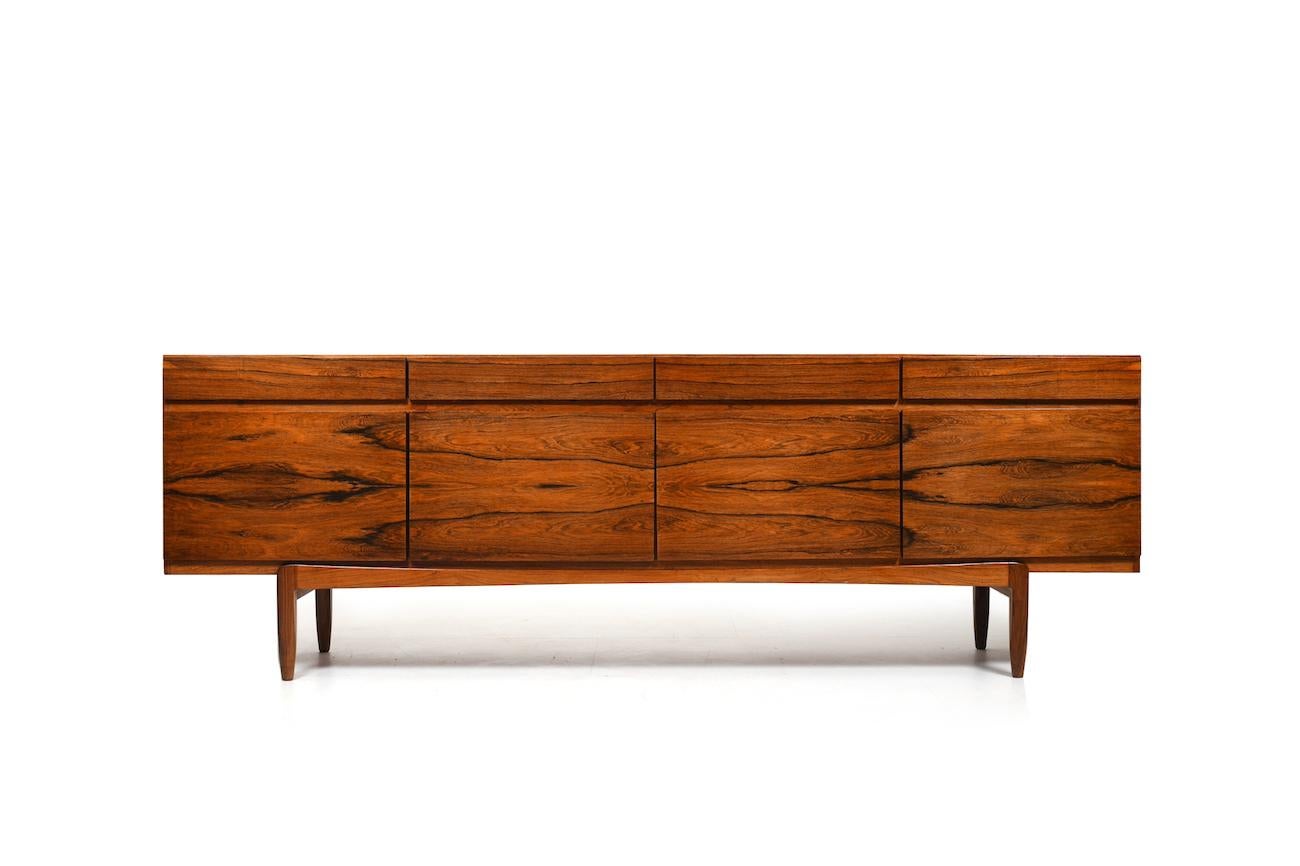 Fine danish sideboard in rosewood veneer, model FA66 by Ib Kofod-Larsen for Faarup Møbelfabrik Denmark 1963. In front with 4 doors and 4 drawers above. Behind one door with more drawers with green filt. High quality danish production. 1960s. Early
