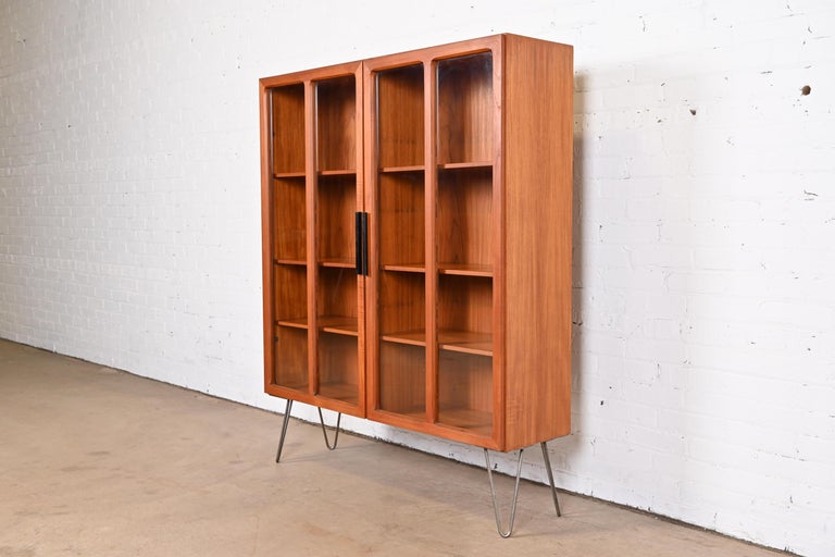 A sleek and stylish mid-century Danish Modern bookcase on hairpin legs

By Ib Kofod-Larsen for Faarup Møbelfabrik

Denmark, 1960s

Sculpted teak, with ebonized handles, glass doors, and steel hairpin legs. Shelves are adjustable and
