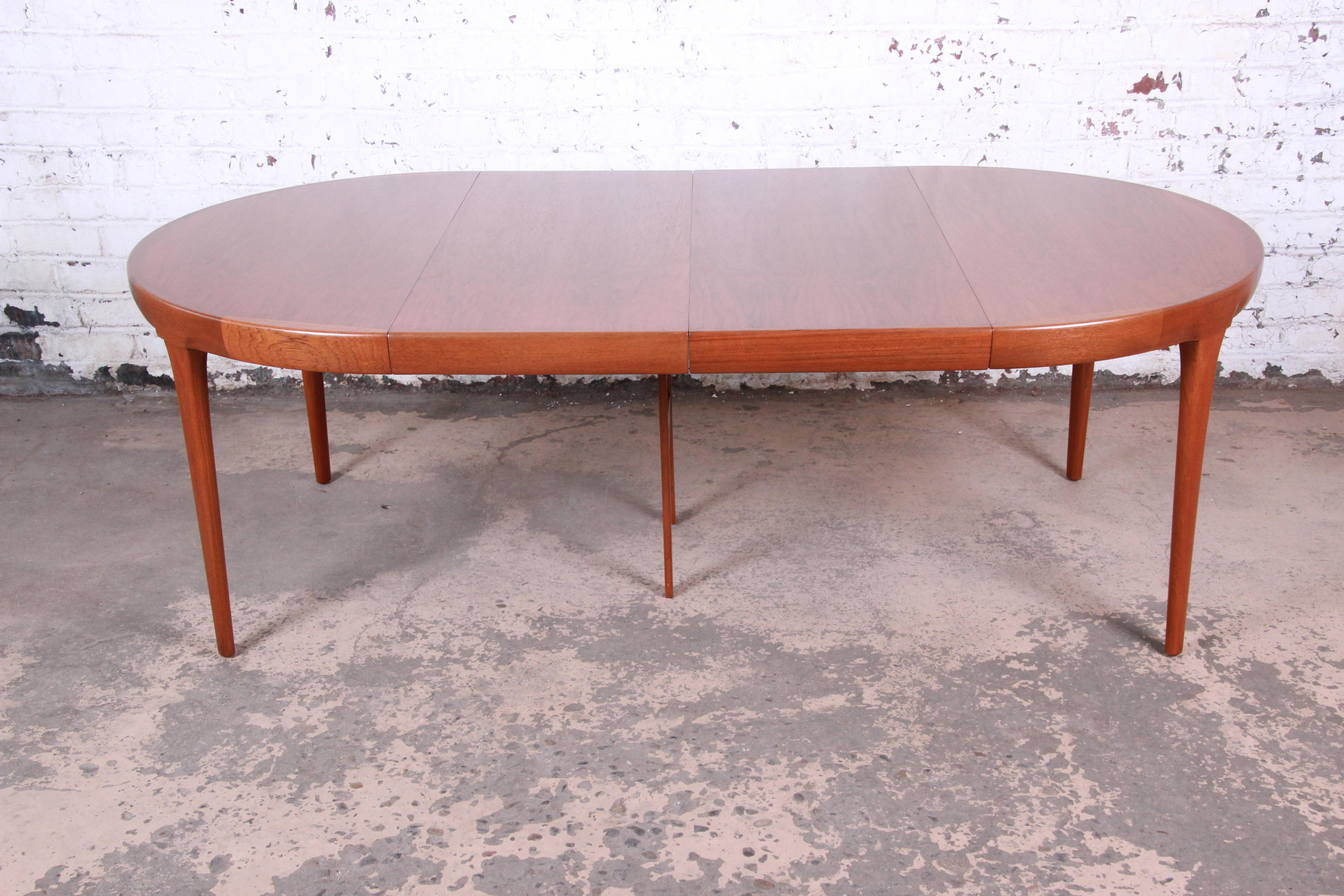 An exceptional midcentury Danish modern teak extension dining table designed by Ib Kofod-Larsen for Faarup Møbelfabrik. The table features gorgeous teak wood grain with solid sculpted teak legs and sleek Scandinavian design. Made in Denmark, circa