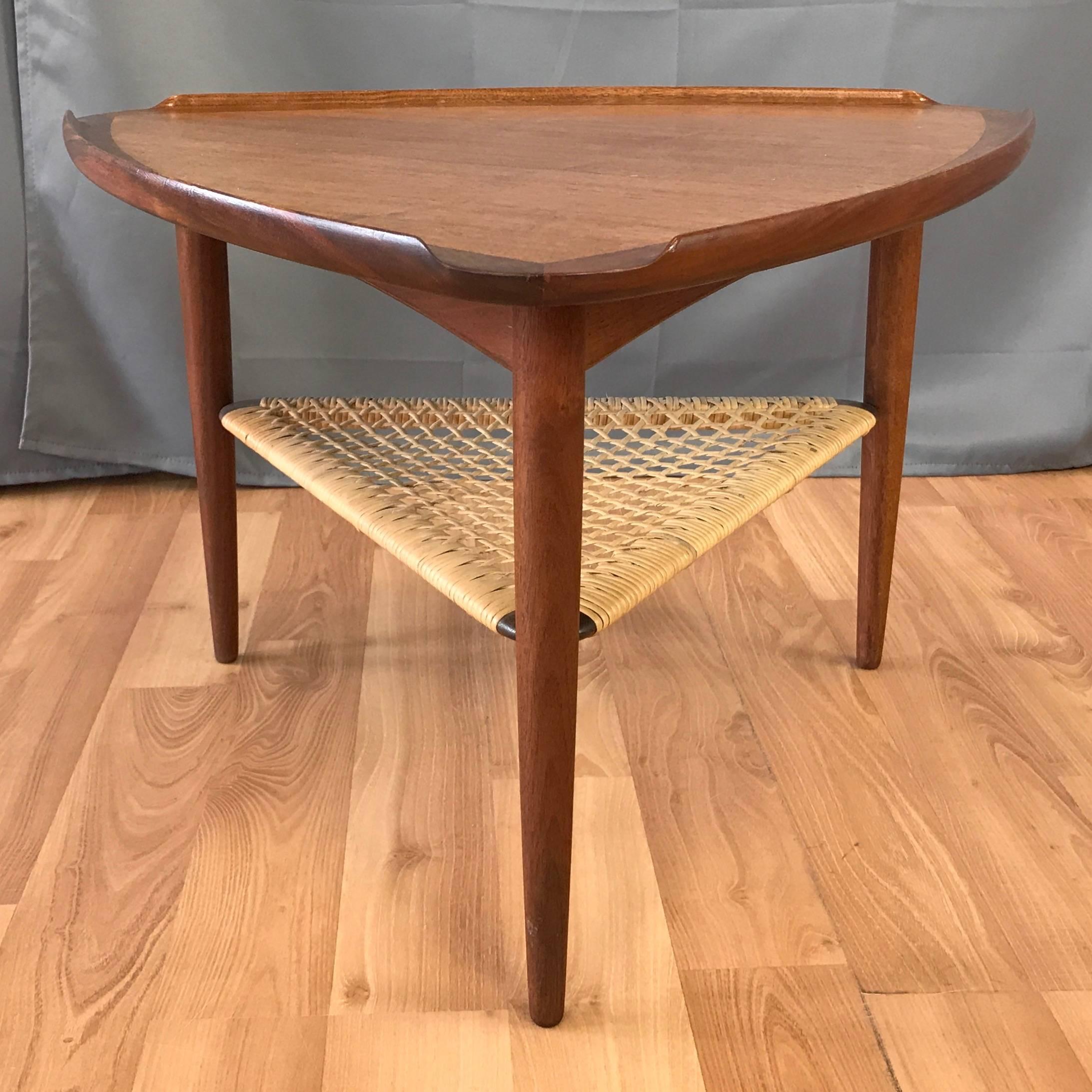 A model #17-15 “Wedge” table in teak with woven cane shelf by Ib Kofod-Larsen for Selig.

Classic Danish modern cocktail or side table with expertly crafted rounded triangular top featuring bookmatched grain and smoothly sculpted raised lip edges.