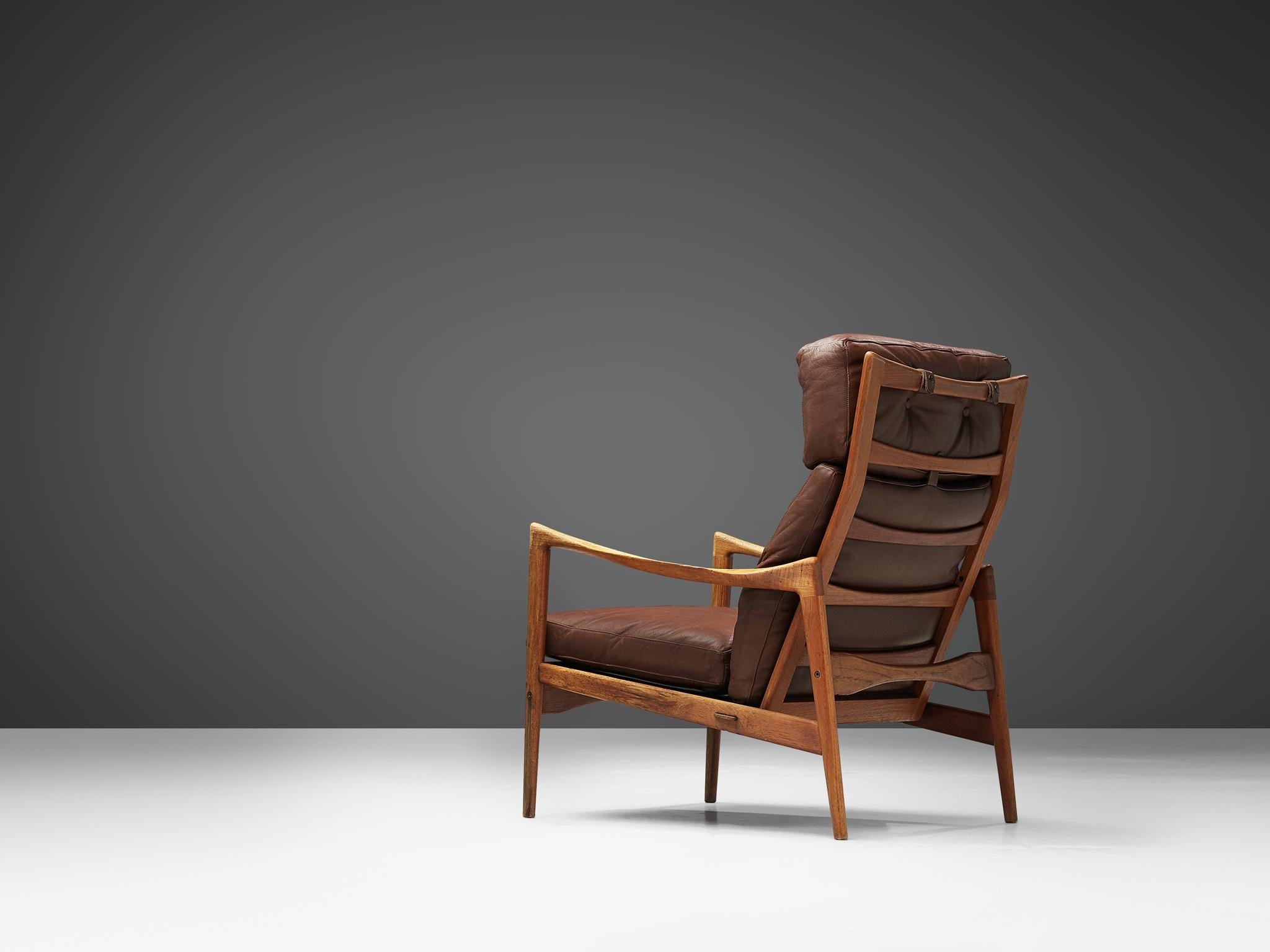 High back chair, in teak and leather, by Ib Kofod-Larsen for OPE Möbler, Sweden, circa 1963.

Elegant high back armchair in teak and brown leather upholstery. The frame shows the great skills of Ib Kofod-Larsen. Elegant lines and curves and a