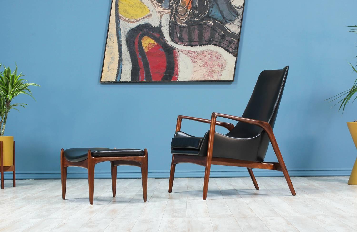 Elegant Lounge chair with ottoman designed by Ib-Kofod Larsen and manufactured by Selig in Denmark circa 1960’s. Both items feature a walnut-stained beech wood sculptural frame upholstered in high quality full grain black leather. This classy high