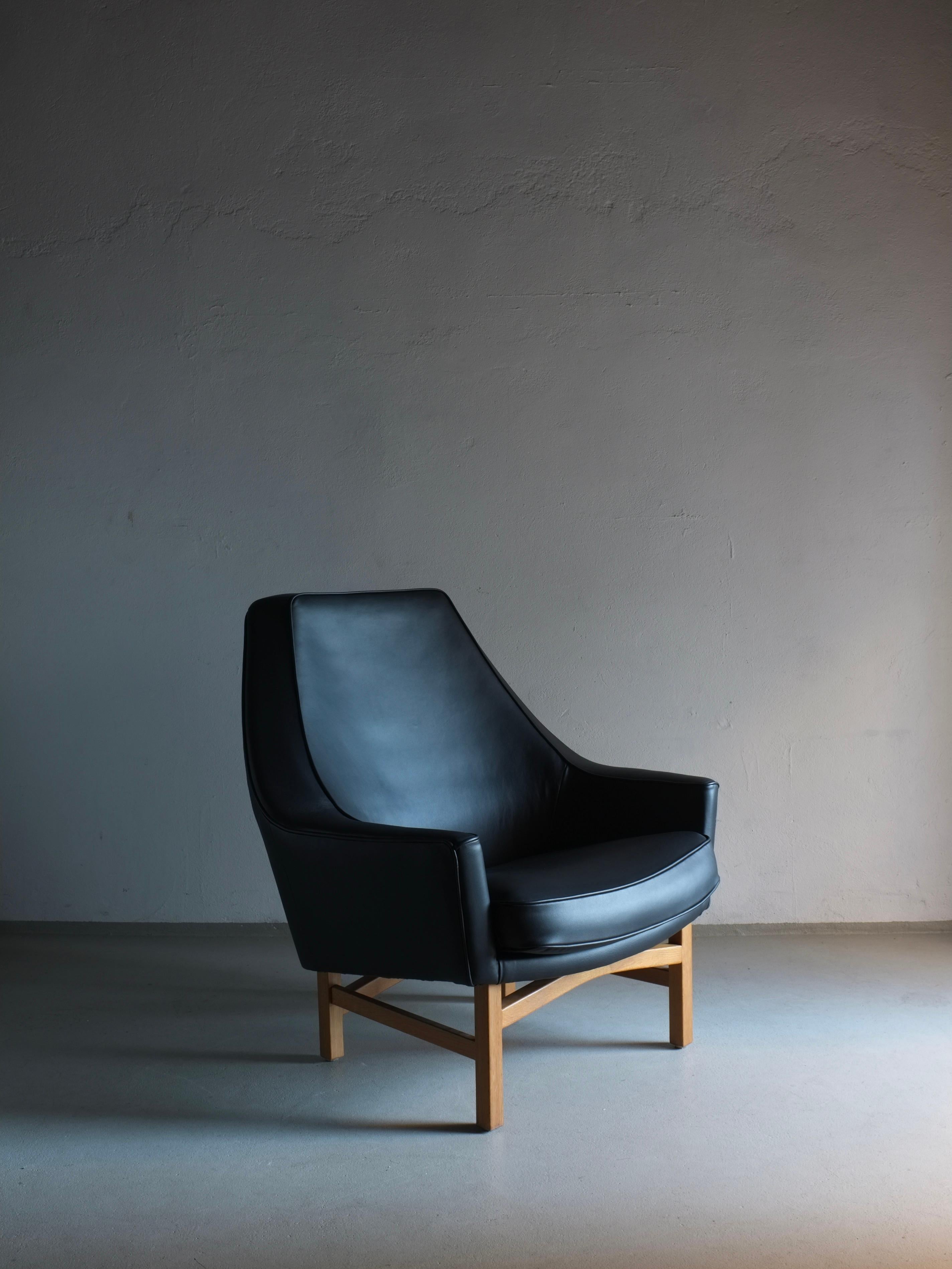 Black leather lounge chair with an oak wooden base designed by IB Kofod-Larsen for OPE. Rare 