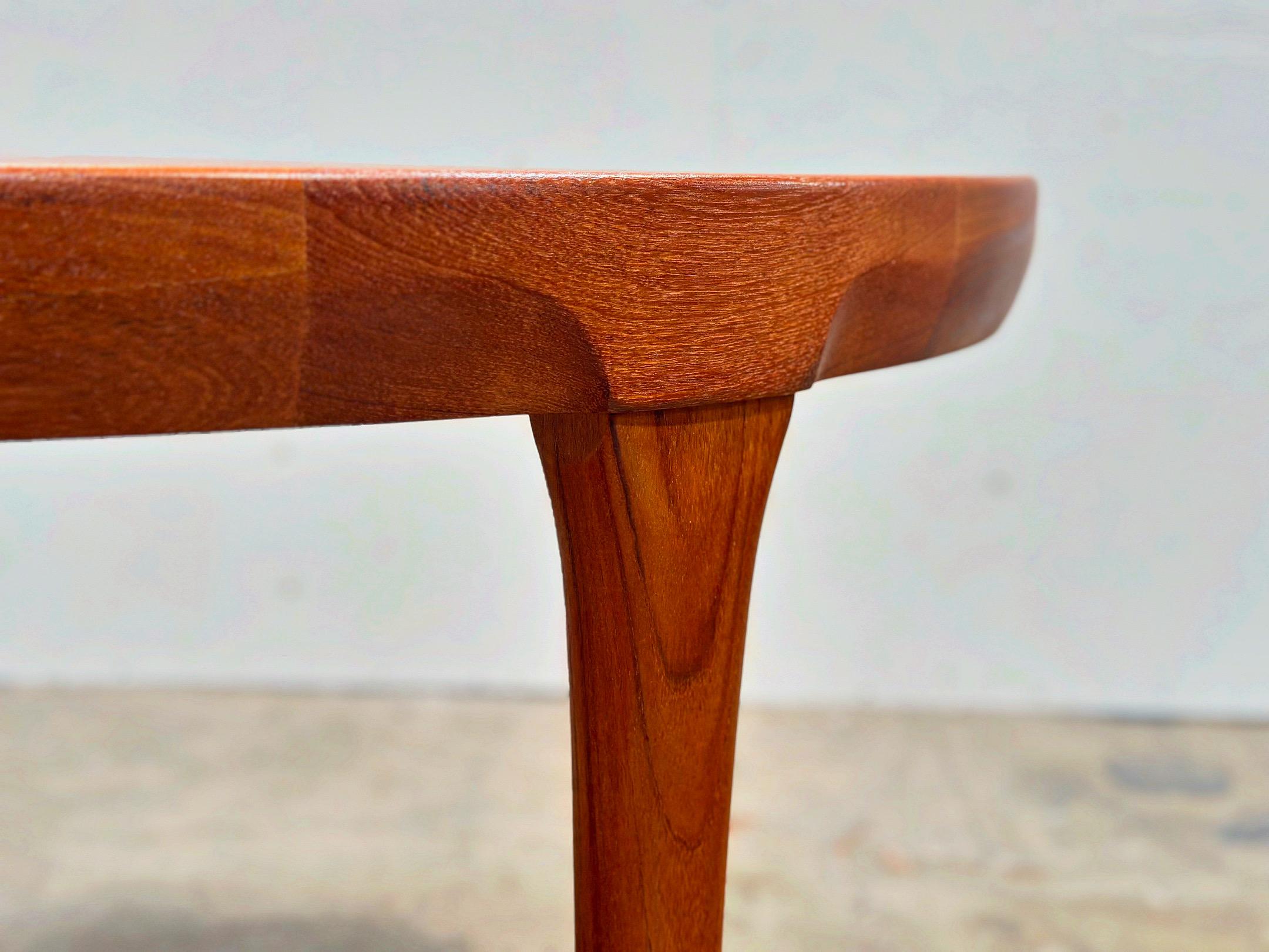 Stellar mid century Danish modern dining table in old growth teak by Ib Kofod Larsen for Faarup Mobelfabrik. Exaggerated sculpted apron and solid teak legs. Versatile size ranging from a 47” diameter round table to a generous oval at 86” with both
