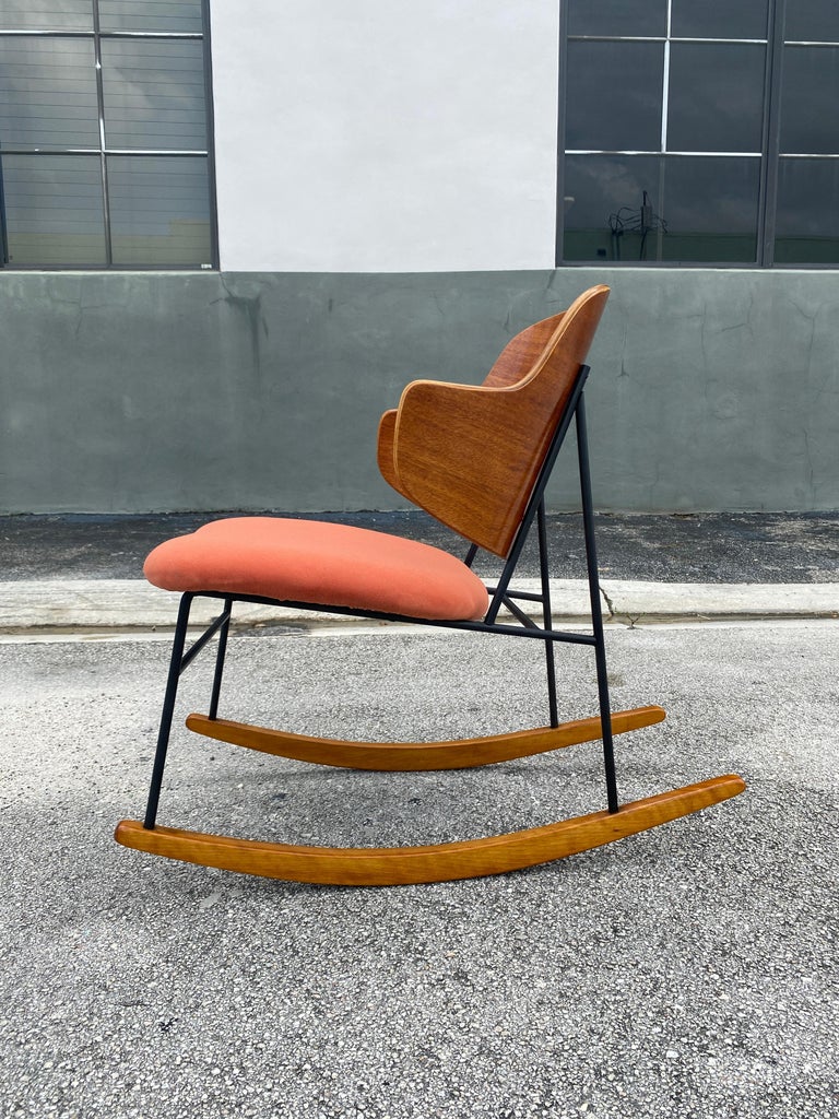 Classic Danish modern Kofod-Larsen penguin rocking chair. Featuring a sturdy black wrought Iron framework with capped feet, slightly slanted and upholstered burnt orange velvet seat with comfortable angled molded Birch seat back. Circa