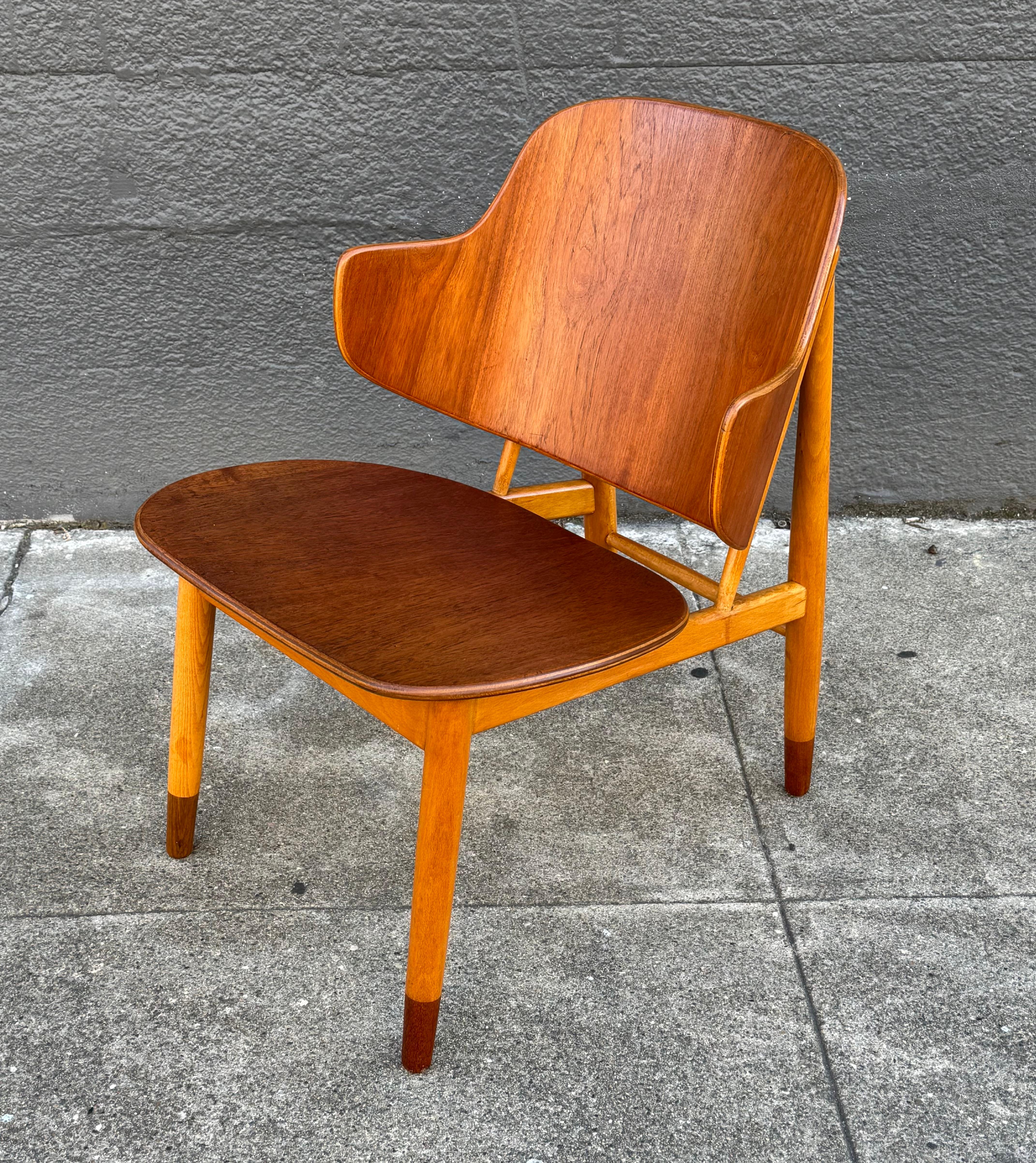 Silla Pingüino de maderas mixtas de Ib Kofod-Larsen de Dinamarca. Construido en madera de haya para el armazón, con un asiento ancho y un respaldo alado de teca figurativa, así como  los extremos de las piernas. Una forma muy arquitectónica que