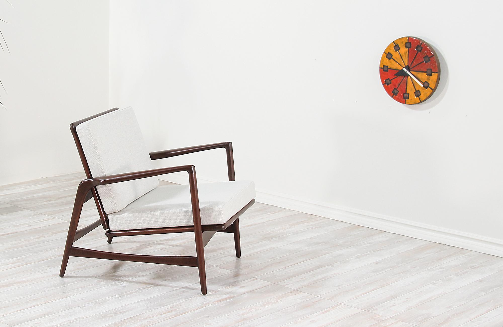 Sleek reclining lounge chair designed by Ib Kofod-Larsen for Selig in Denmark, circa 1960s. This sculptural chair features a solid wood richly grained frame with angled armrests, back, and legs adding ergonomic support with clean lines and modern