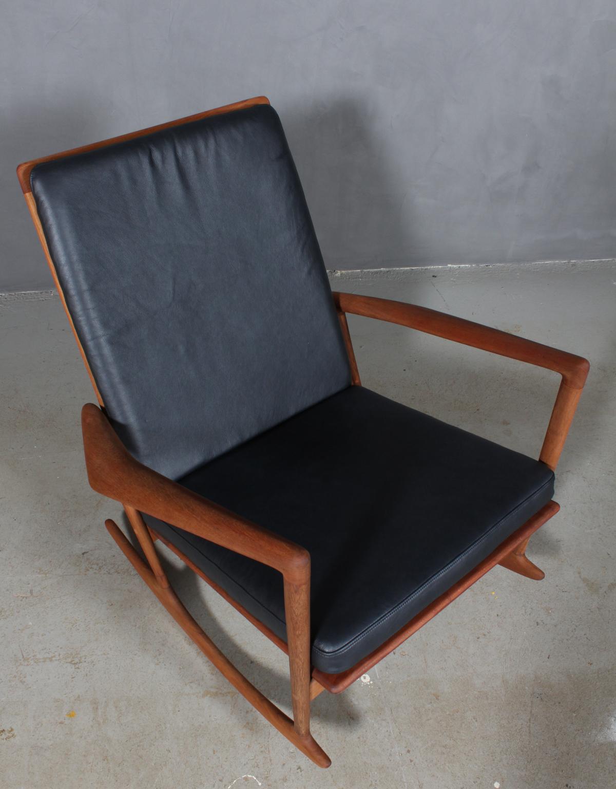 Ib Kofod Larsen rocking chair new upholstered with black aniline leather.

Frame with sculptural arm leans in solid teak.

Model 650-15, made by Christian Linneberg.