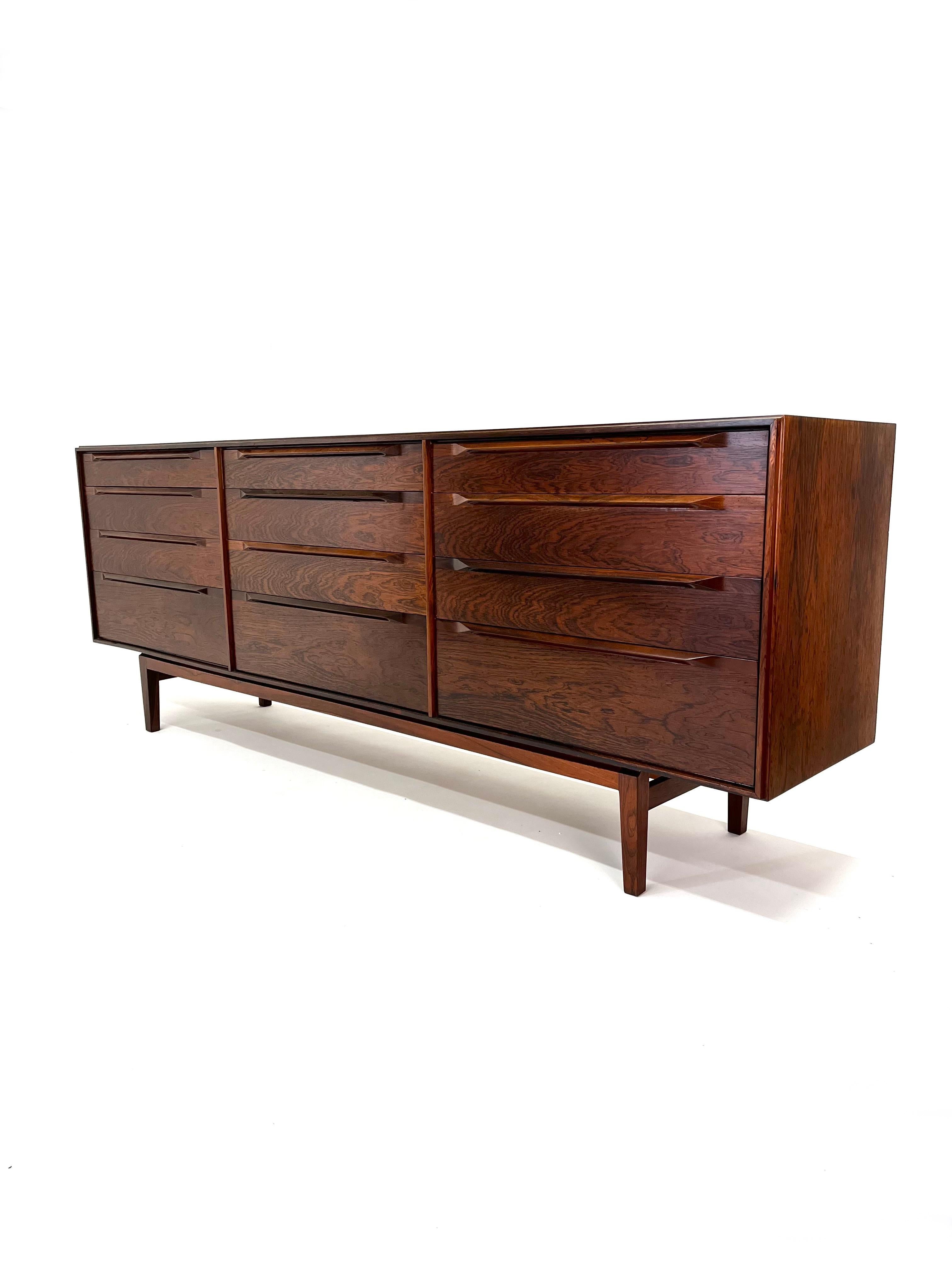 Designed by Ib Kofod-Larsen, this rarely seen rosewood 12 drawer cabinet is beautifully constructed with dove-tailed drawer fronts with sculpted drawer pulls. It is perfectly suited for use as a dresser or credenza. The case is supported by solid