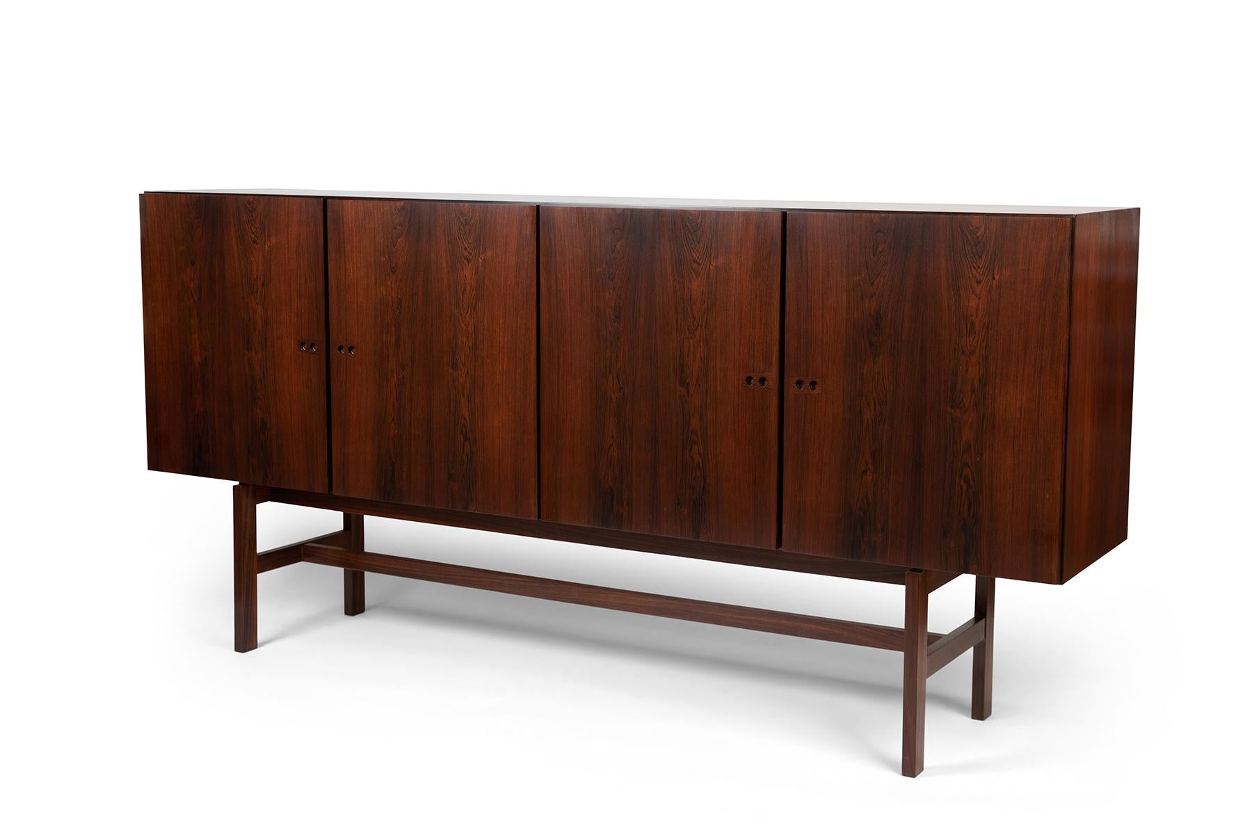 1960s minimal and elegant rosewood cabinet by Danish designer Ib Kofod-Larsen features several interior shelves and lined drawers for storage. The left side has a light source within that illuminates when open. This chest has been newly and