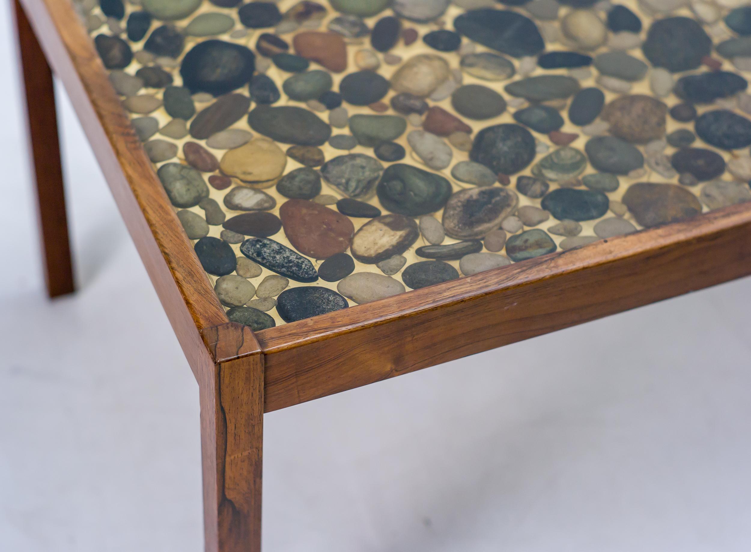 Teak coffee table designed by Ib Kofod-Larsen for Seffle Möbelfabrik.
Remarkable coffee table with a polyester top with cast in natural pebbles.

Ib Kofod-Larsen was born in 1921 in Denmark. Kofod-Larsen was trained as a cabinetmaker with the