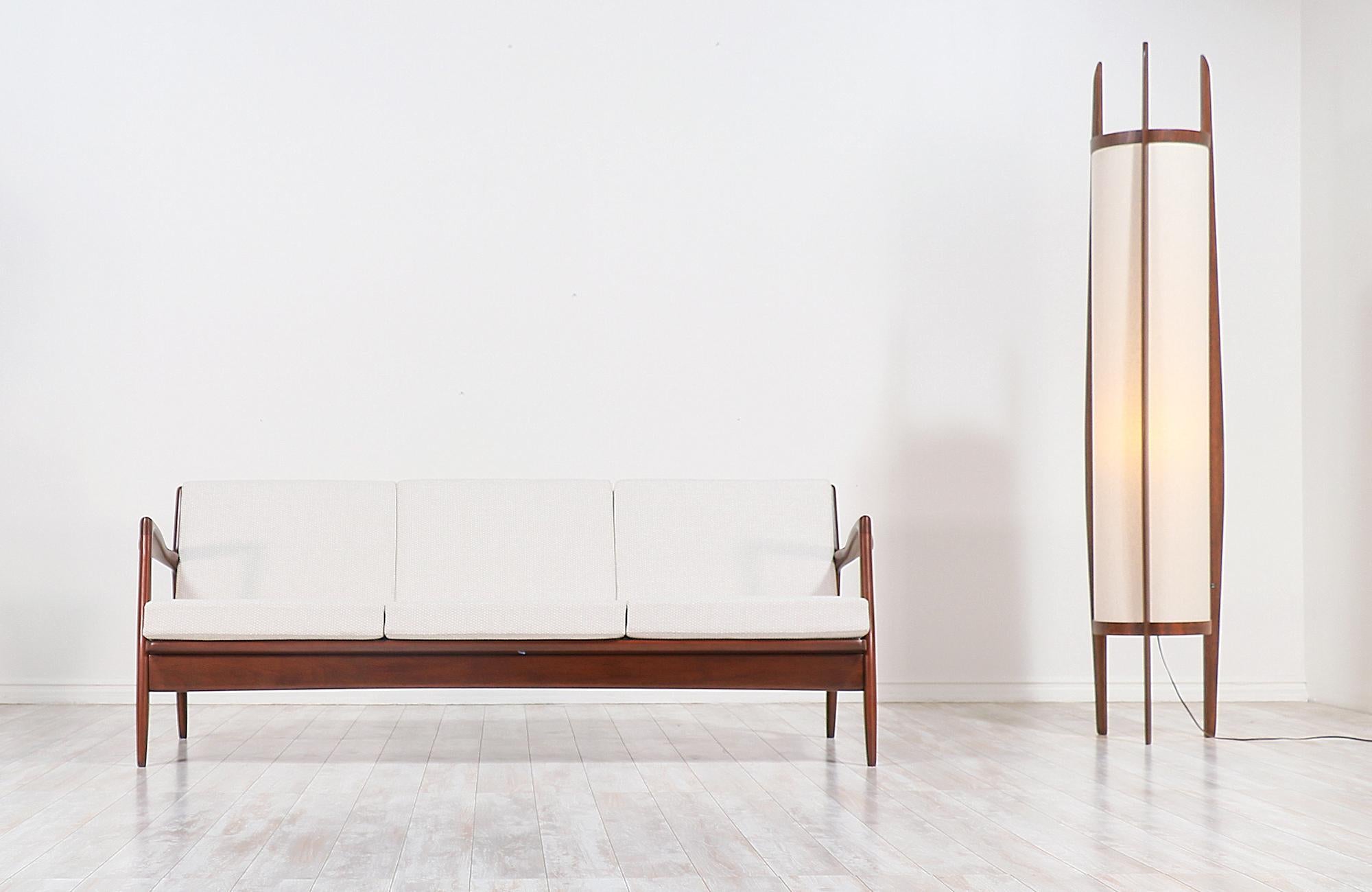 Stylish modern sofa designed by Danish architect and furniture designer Ib-Kofod Larsen for Selig in Denmark circa 1960s. This elegant sofa features a solid sculpted walnut-stained Beechwood frame with vertical slats at the back to create a sleek