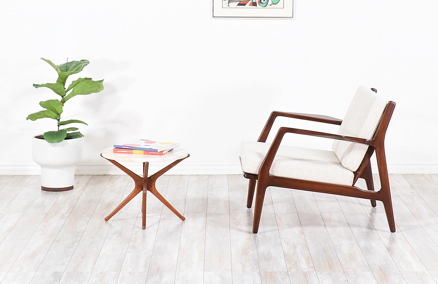 Stylish lounge chair designed by Ib Kofod-Larsen for Selig in Denmark circa 1960s. This sleek and ergonomic lounge chair features a sturdy walnut-stained beech-wood frame with angled legs and a sculptural slatted back that is held in place by bowed