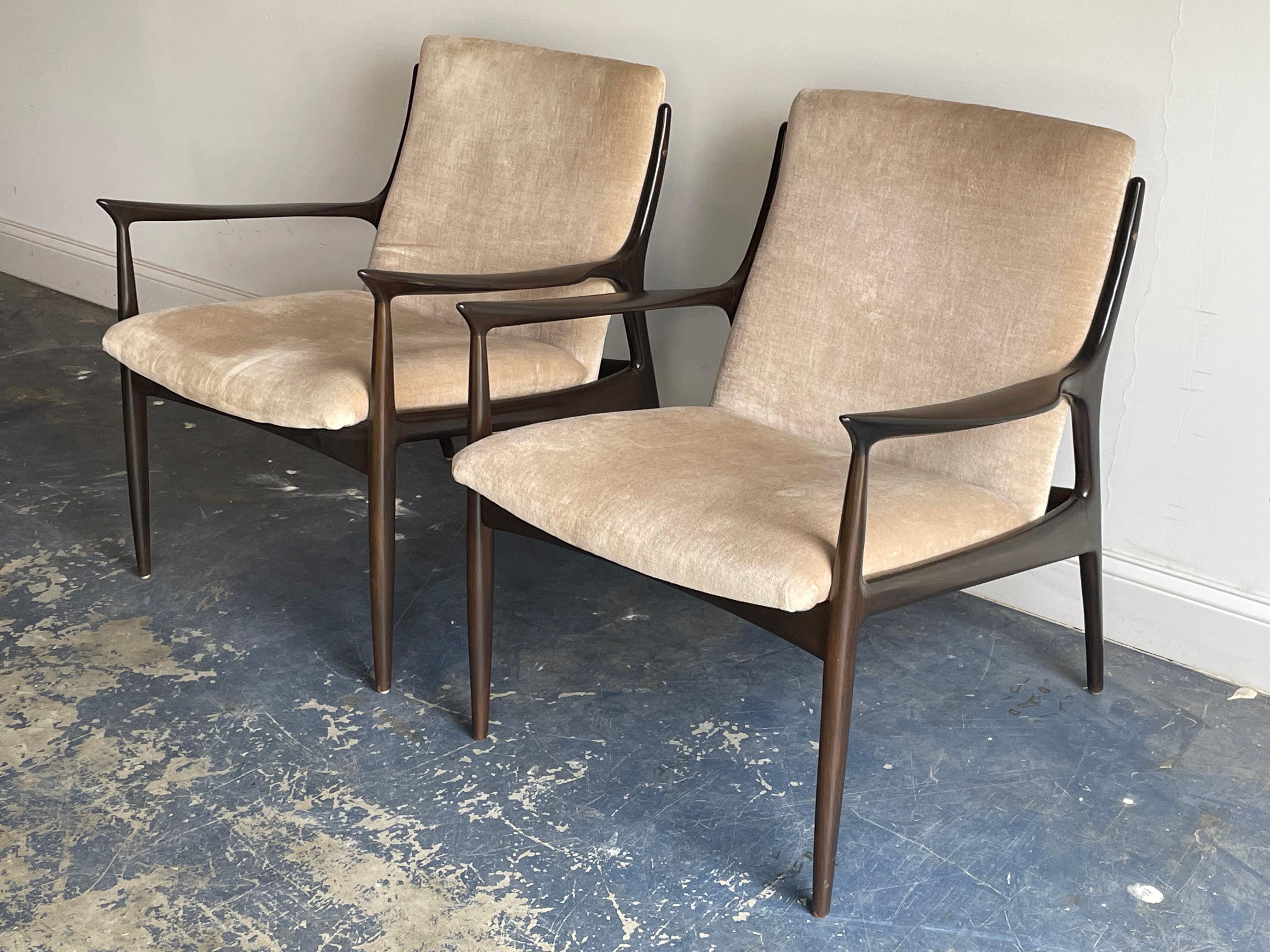 Uncommon pair of sculptural arm chairs designed by Ib Kofod Larsen. Dark walnut tone and velvet upholstery.