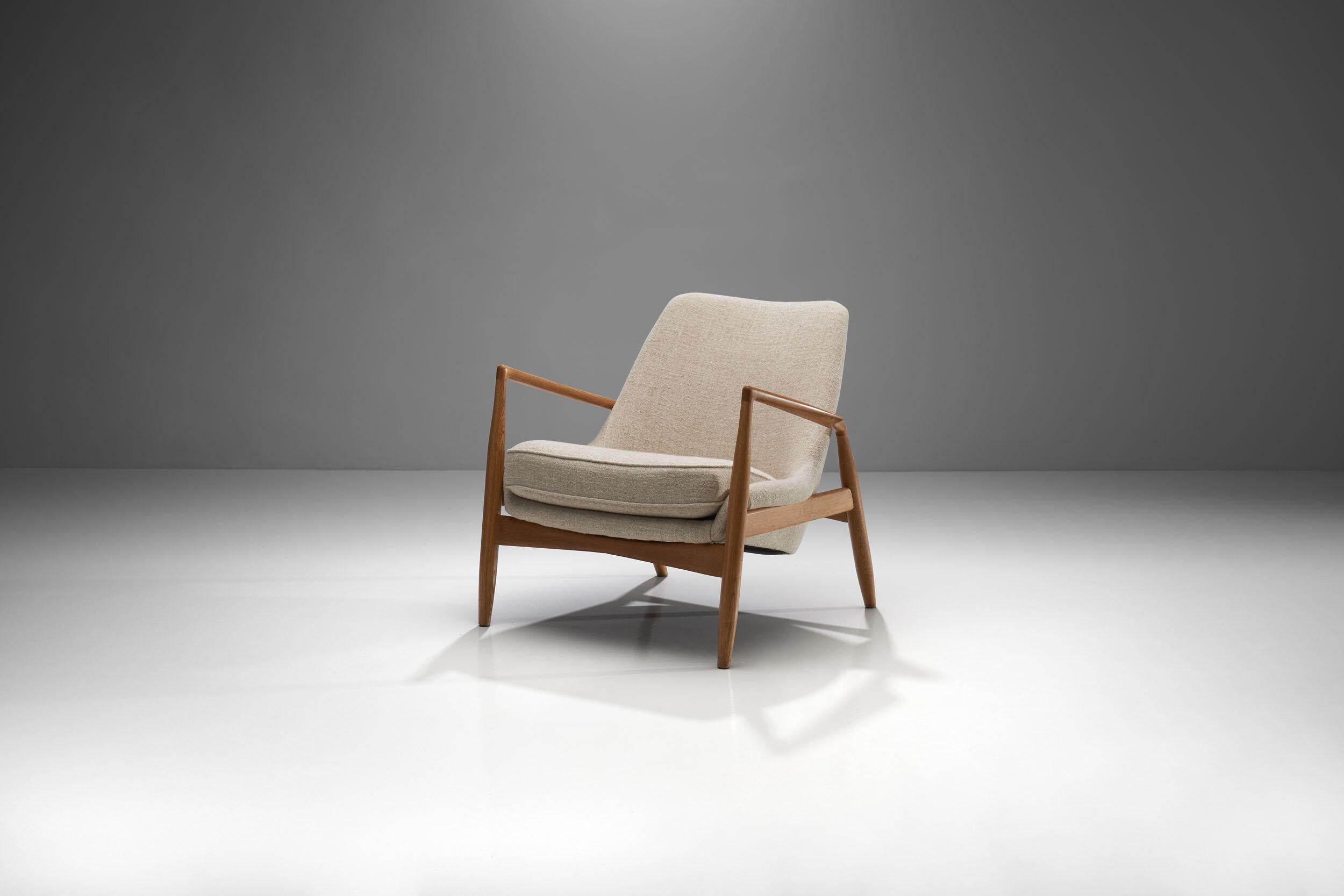 Early version of the 'Seal' lounge chair by Ib Kofod-Larsen in birch, produced by OPE, 1956. Re-upholstered in a light linen blend fabric by Pierre Frey.

The clear lined frame of this chair contrasts beautifully with the angled seating and gives