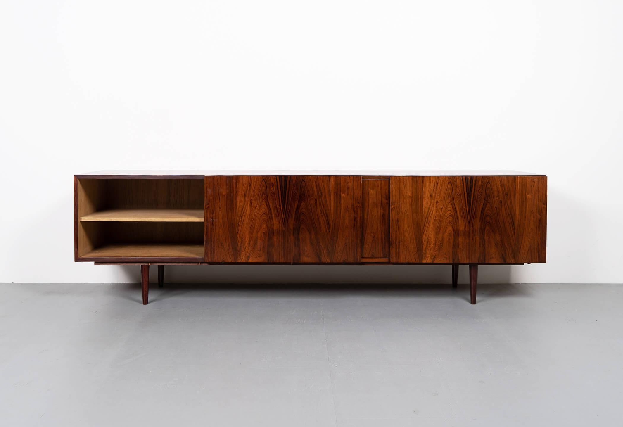Danish sideboard in rosewood designed by Ib Kofod Larsen. Produced in Denmark for Faarup Møbelfabrik in the 60s. This piece has 3 compartments with sliding doors and adjustable height shelves. The middle compartment features 2 drawers.

Original
