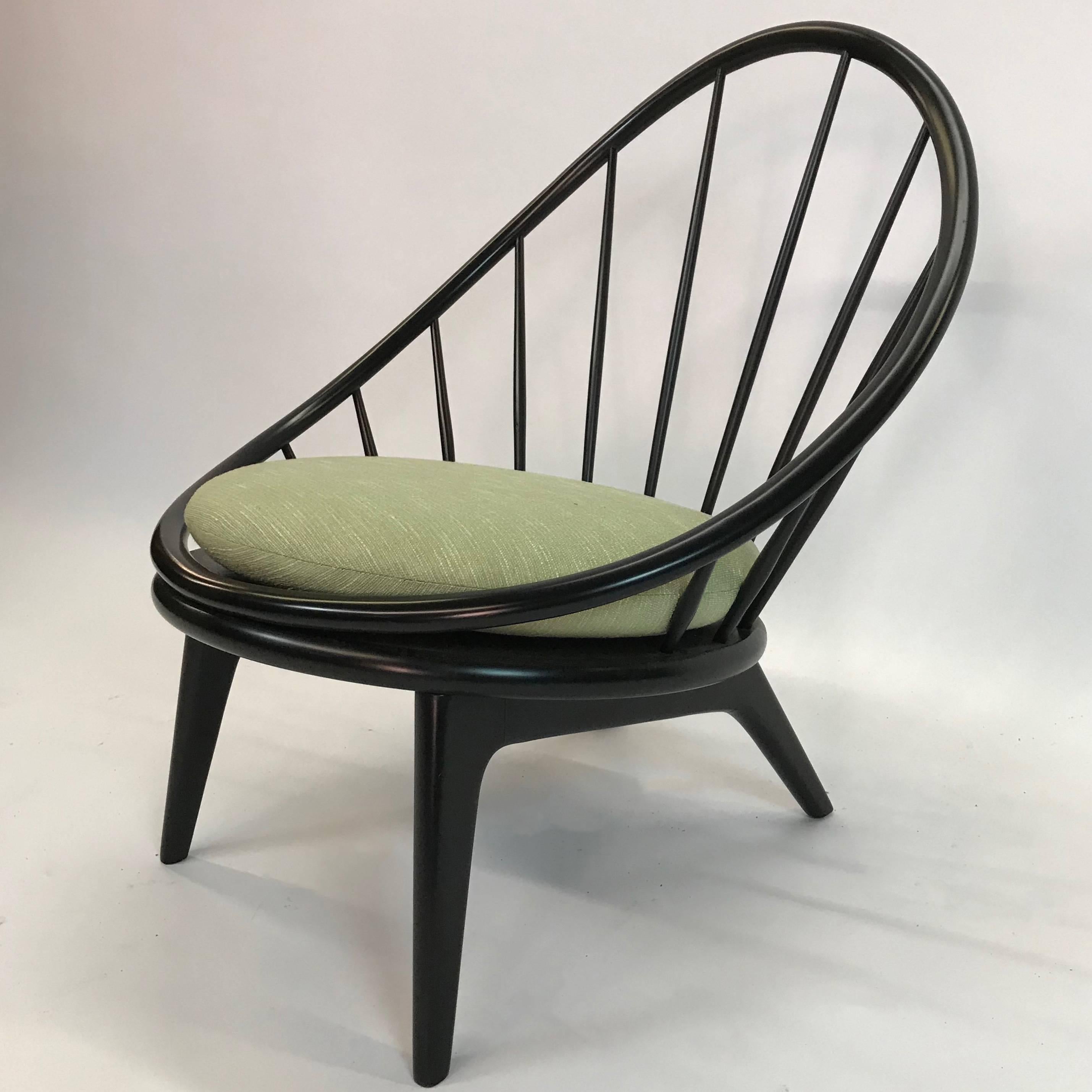 Early, Ib Kofod-Larsen peacock or hoop lounge chair features a rounded, ebonized walnut frame with spindle back. The newly upholstered chenille seat cushion is 20 inches diameter.