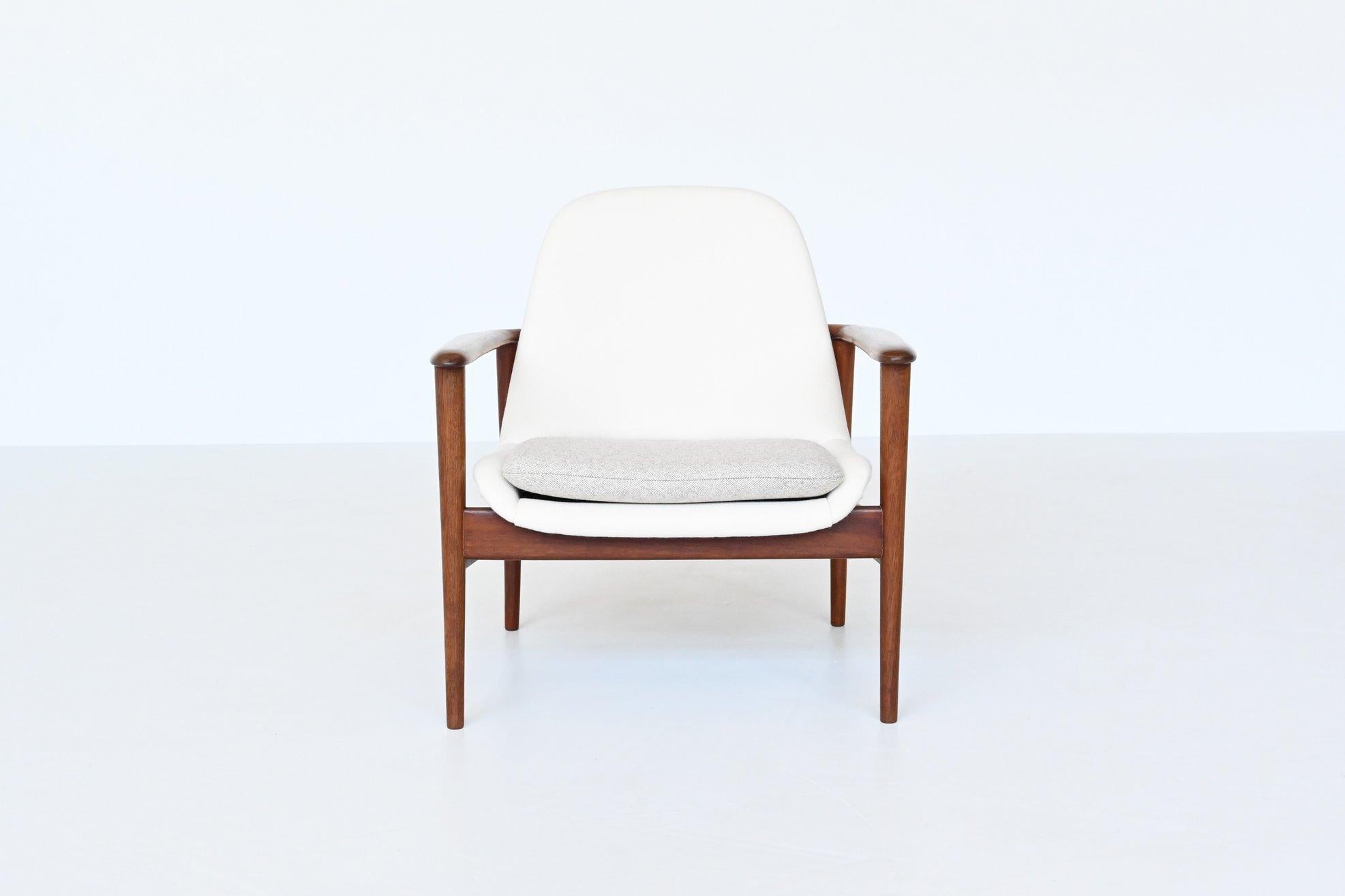Beautiful shaped Scandinavian lounge chair in the style of IB Kofod Larsen and Arne Hovmand-Olsen, Denmark 1960. This chair has a solid teak wooden frame and it is newly upholstered with white and grey wool upholstery. The teak wooden frame flows